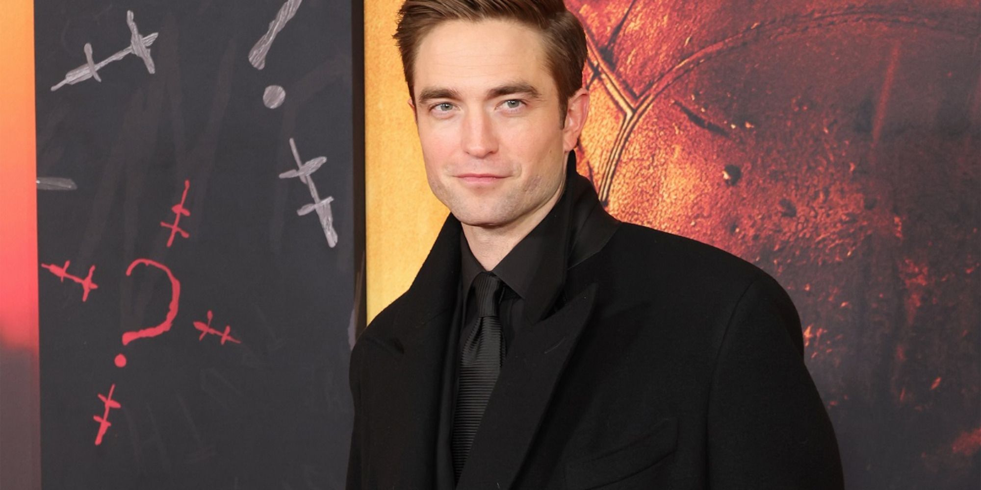 El actor Robert Pattinson en el estreno de "The Batman", sonriendo para las cámaras.