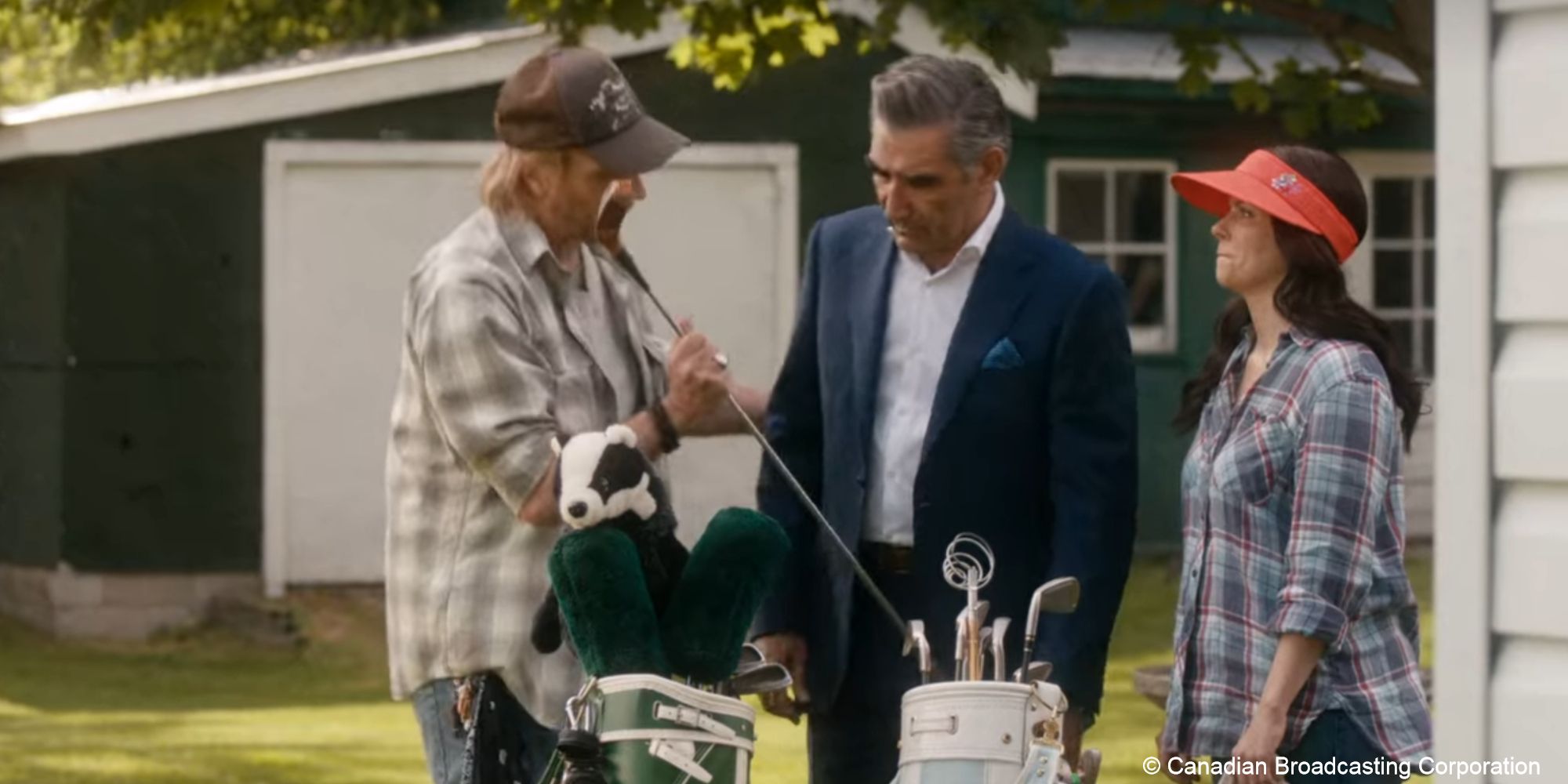 Roland and Johnny handle golf clubs while Stevie watches with amusement
