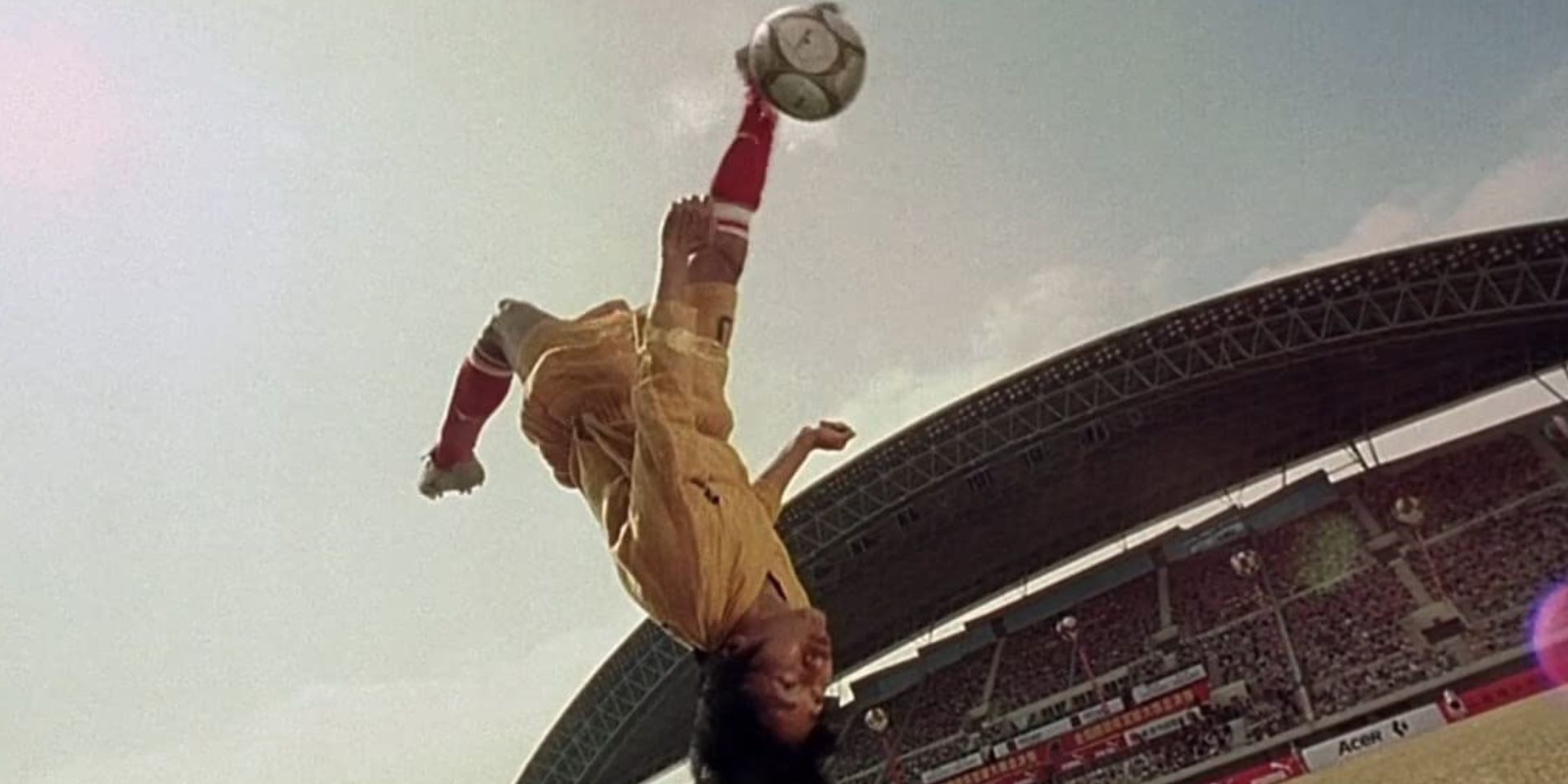 A player kicks a soccer ball while upside down in the air