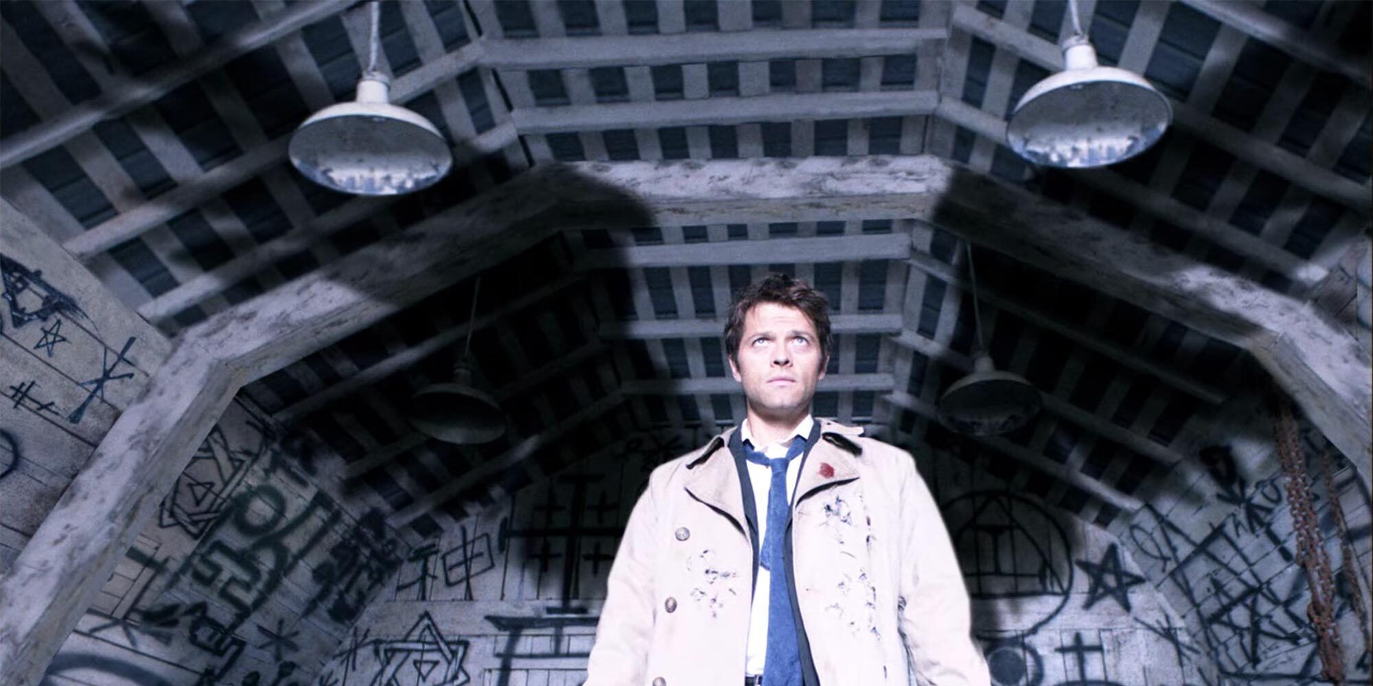 Castiel, wings exposed, with angel and devil traps on the walls around him.