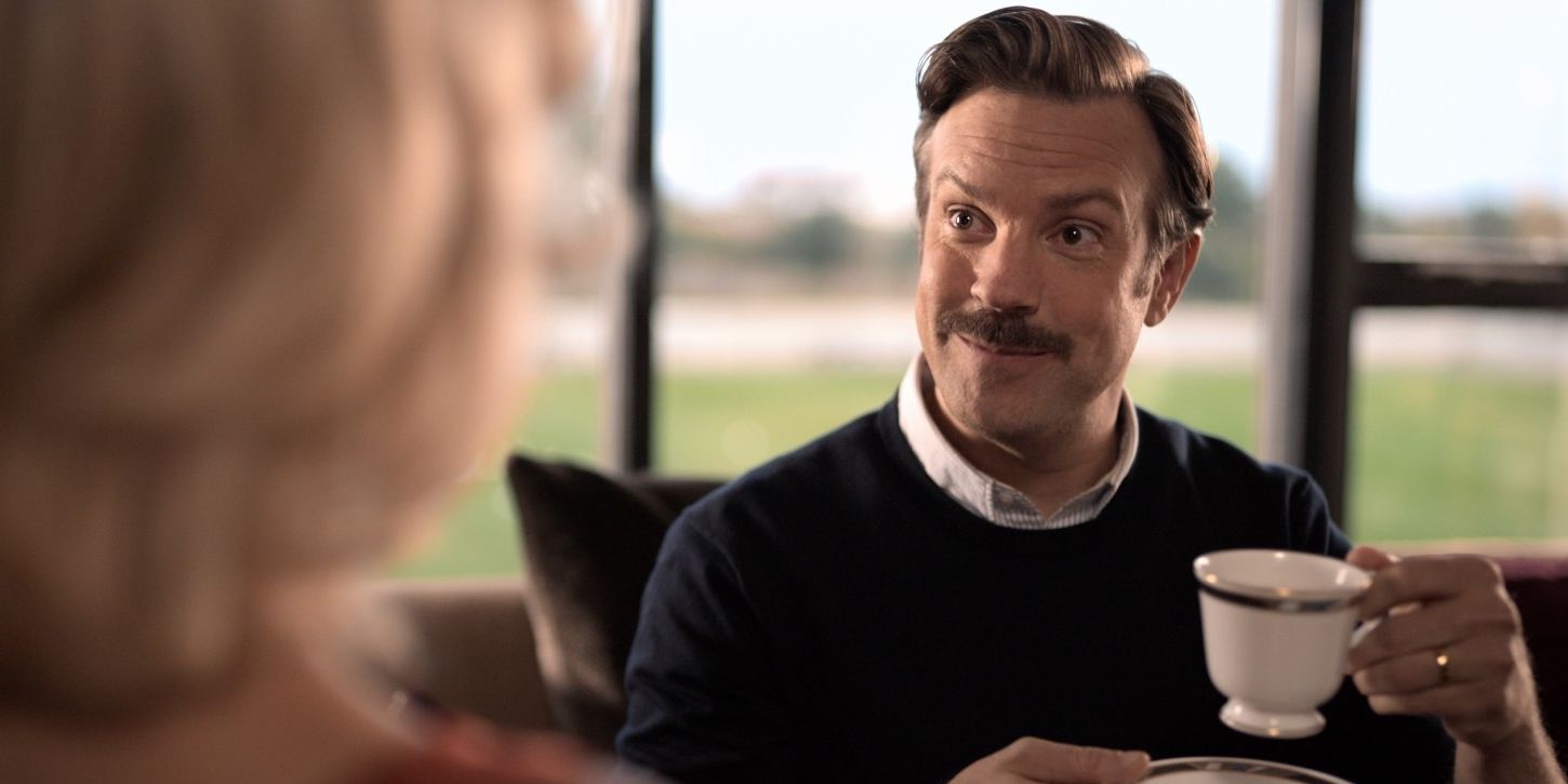 Ted Lasso sharing tea hot brown water and biscuits with rebecca in her office