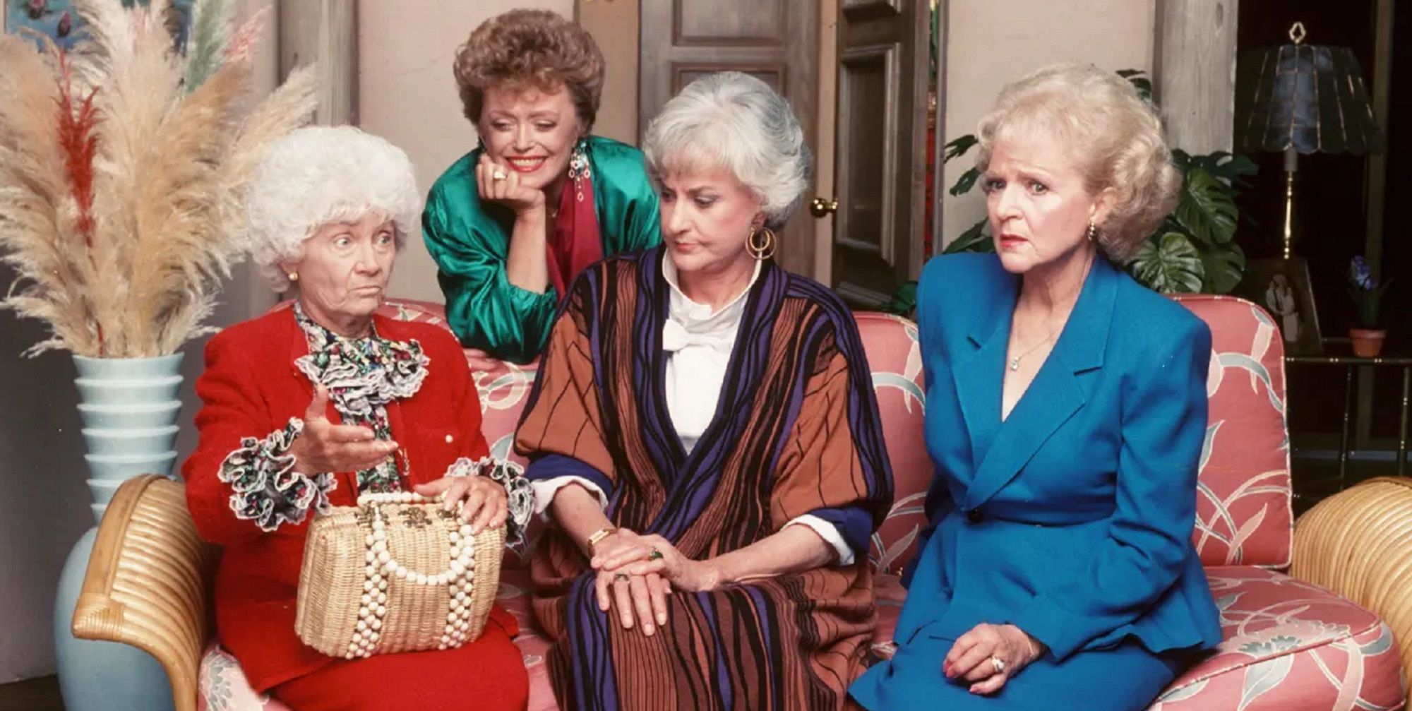 Three women sitting on a couch and one women standing behind them