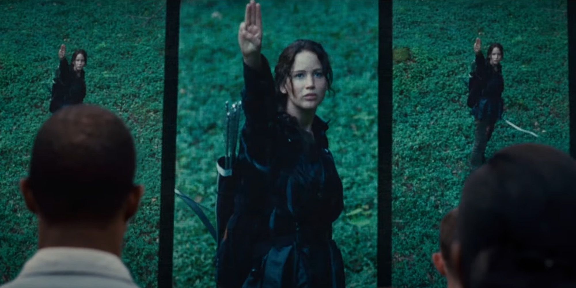 Jennifer Lawrence on a screen giving a signal in The Hunger Games
