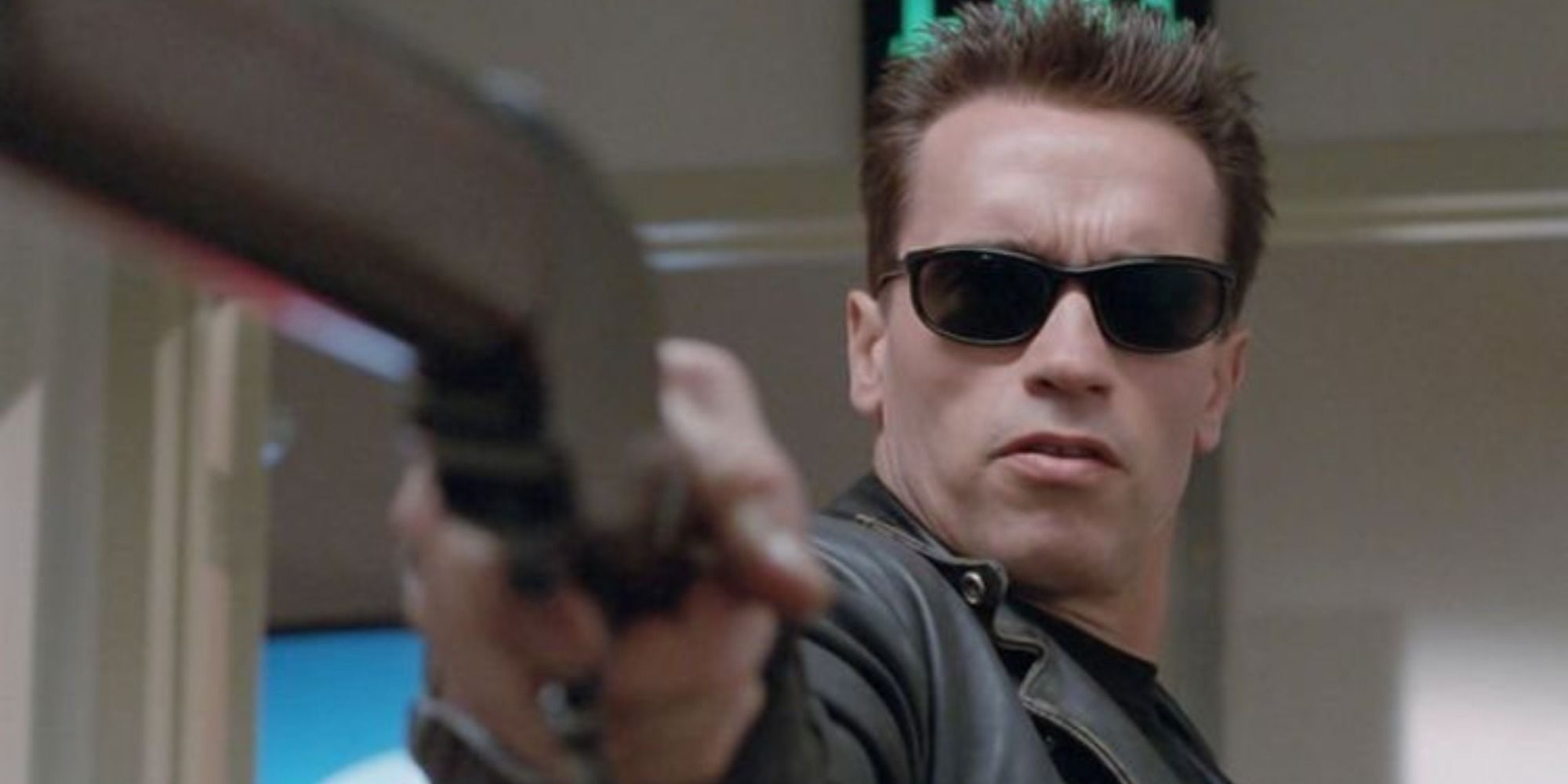 Arnold Schwarzenegger as Terminator wearing sunglasses and pointing gun