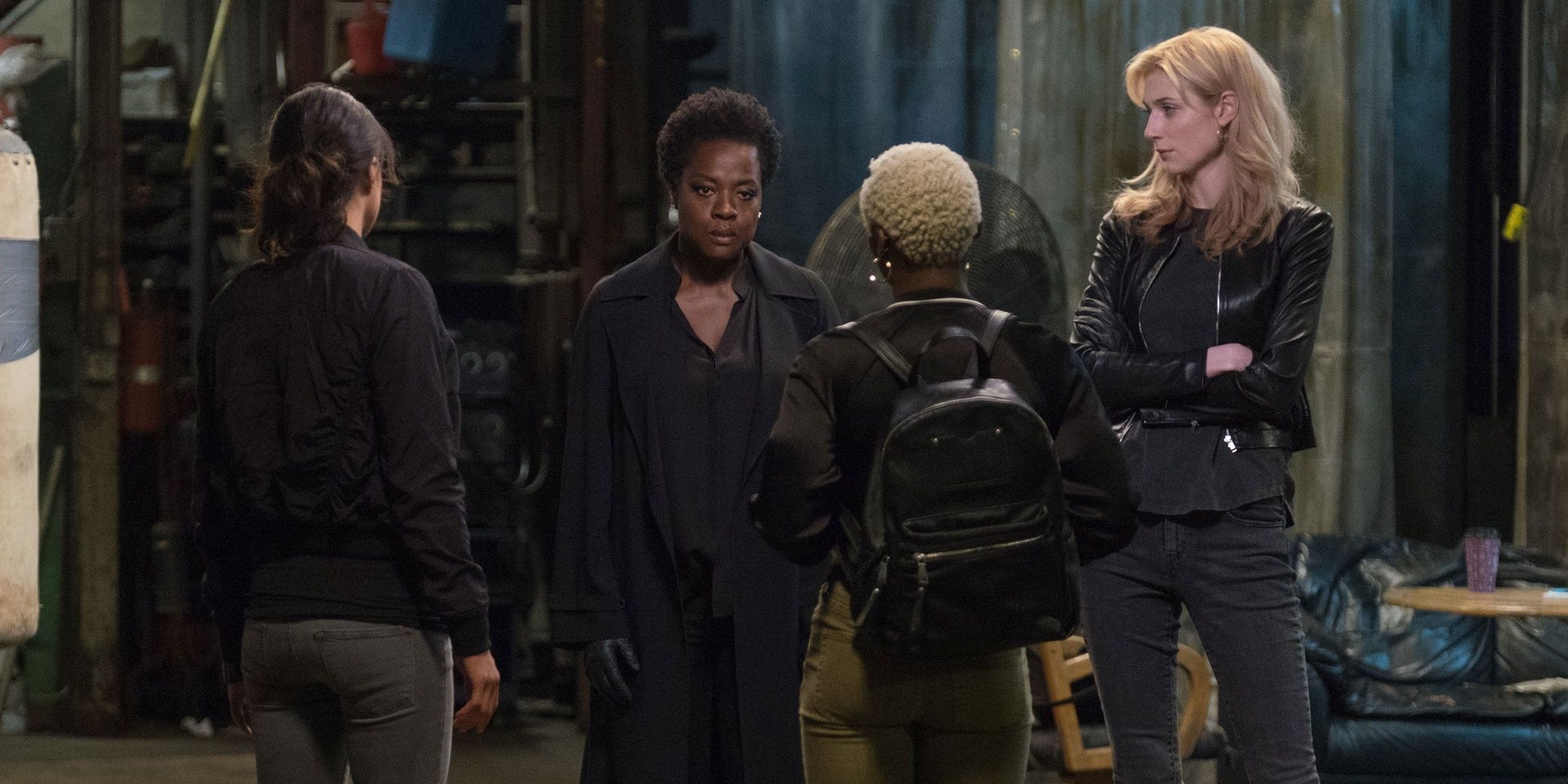 The main cast of the movie Widows talking in a dilapidated space.