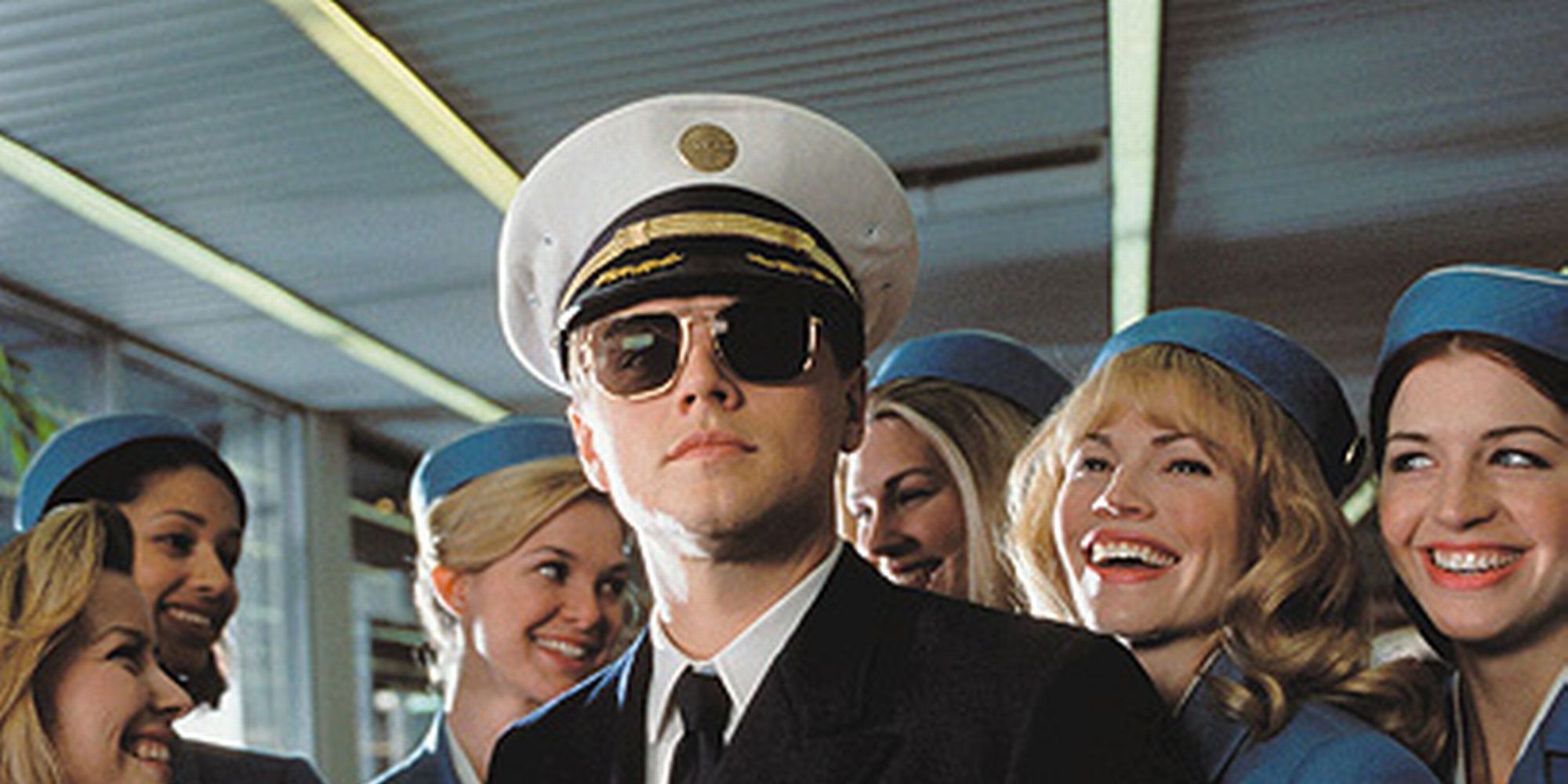 Leonardo DiCaprio as Frank Abegnale Jr dressed as a pilot standing in front of stewardesses in Catch Me If You Can