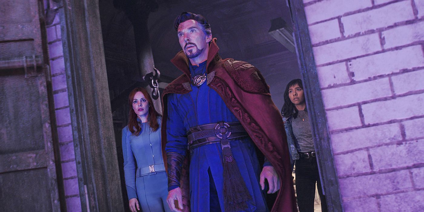 Benedict Cumberbatch as Doctor Strange in Doctor Strange in the multiverse of Madness -- he stands in an open doorway in purple lighting looking at something out of frame