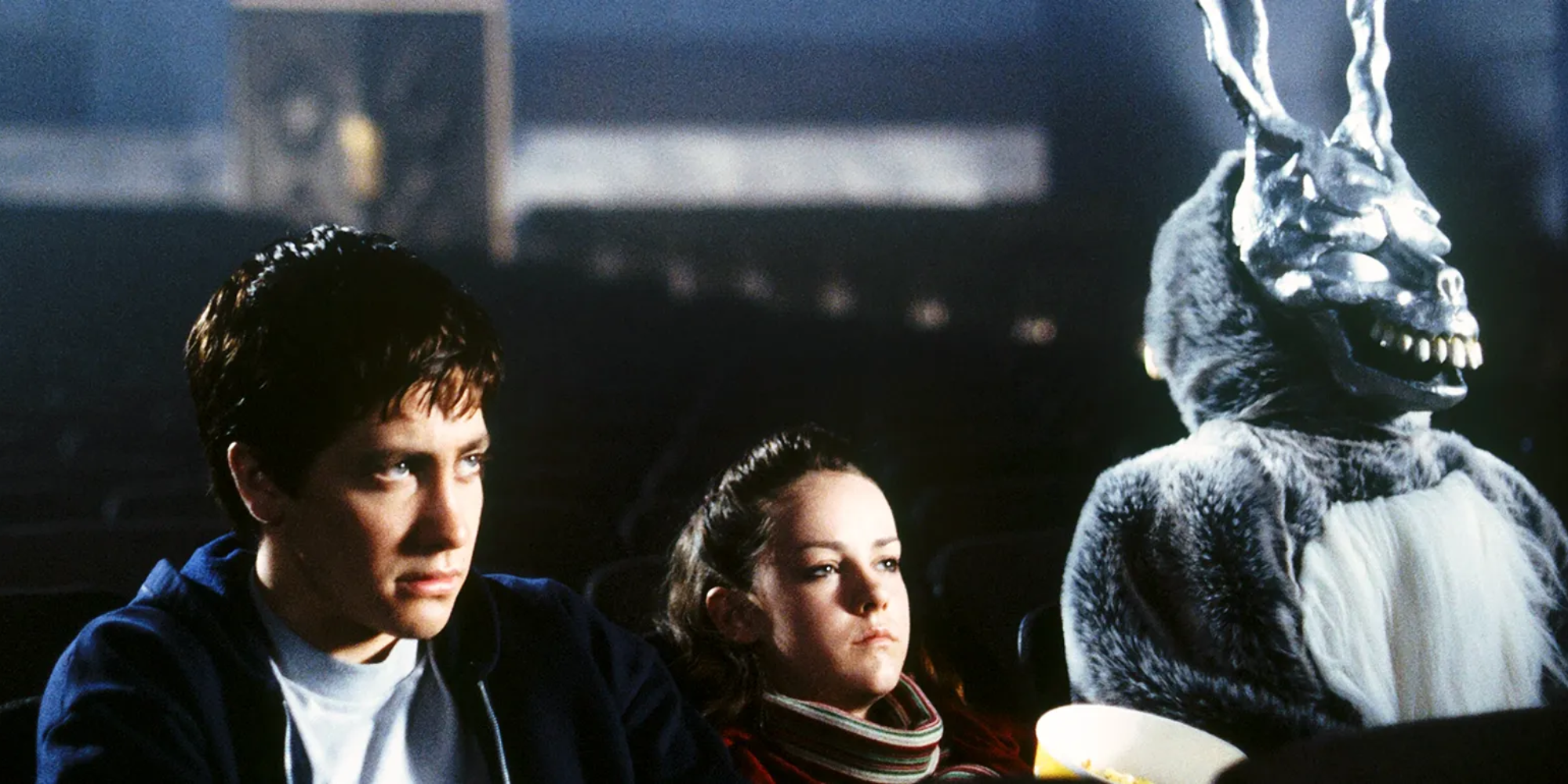 Donnie Darko, Gretchen Ross, and Frank the Rabbit sit in an empty cinema in 'Donnie Darko'.