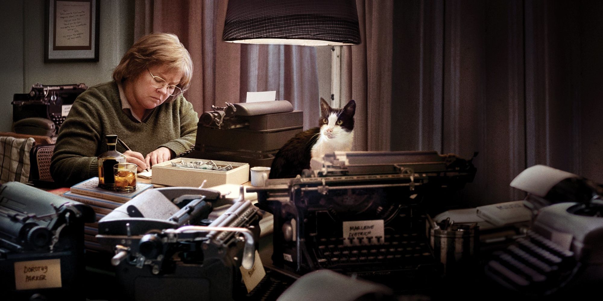 A woman working surrounded with a cat and lots of typewriters