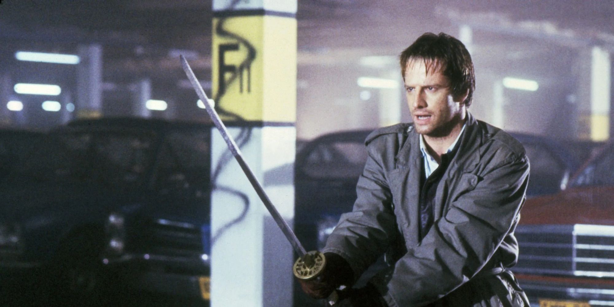 Immortal highlander Connor MacLeod (Christopher Lambert) wields a samurai sword in an underground parking lot.