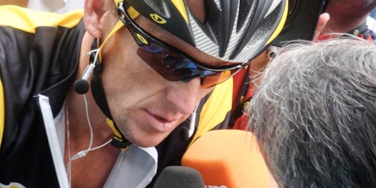 Lance Armstrong interviewed on his bike, helmet and sunglasses
