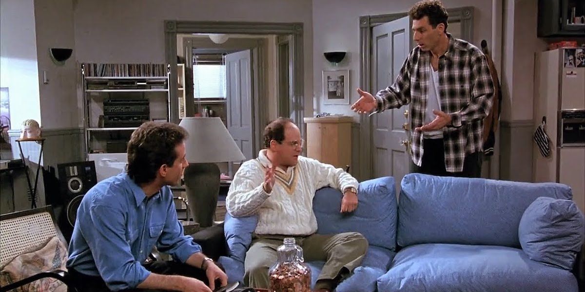Michael Richards as Kramer gesturing and talking to Jerry and Jason Alexander as George on the couch in Seinfeld