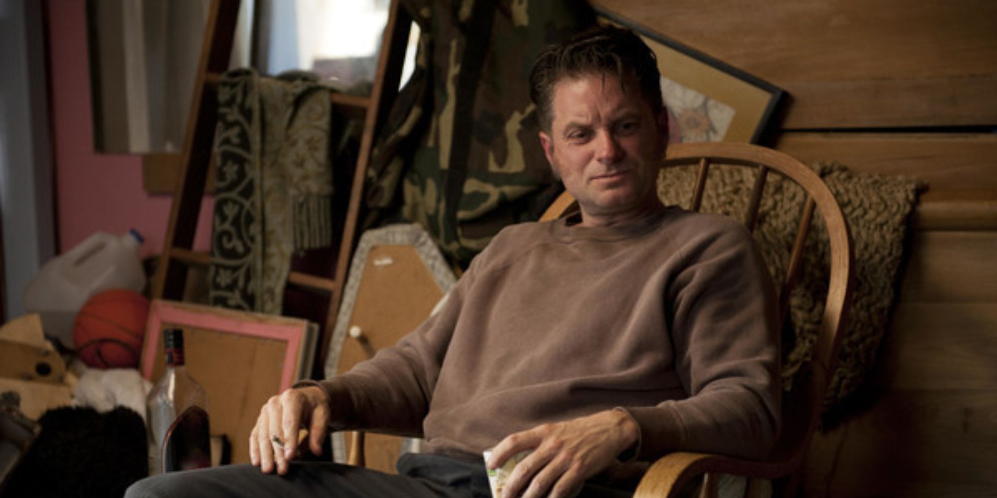 A man sitting on a chair with a mess behind him