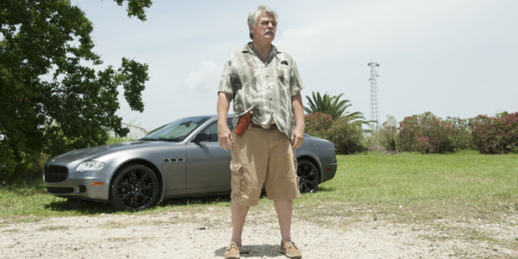 A man standing in the middle of nowhere with a car behind him