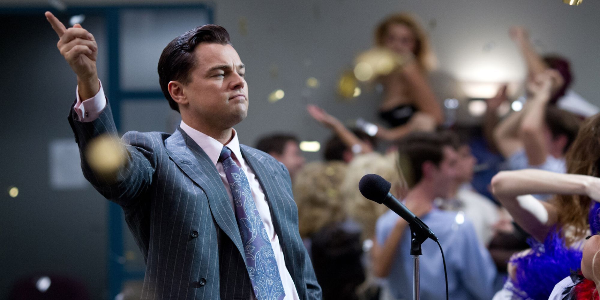 Leonardo DiCaprio as Jordan Belfort raising his hand while addressing a cheering crowd in The Wolf of Wall Street (2013)