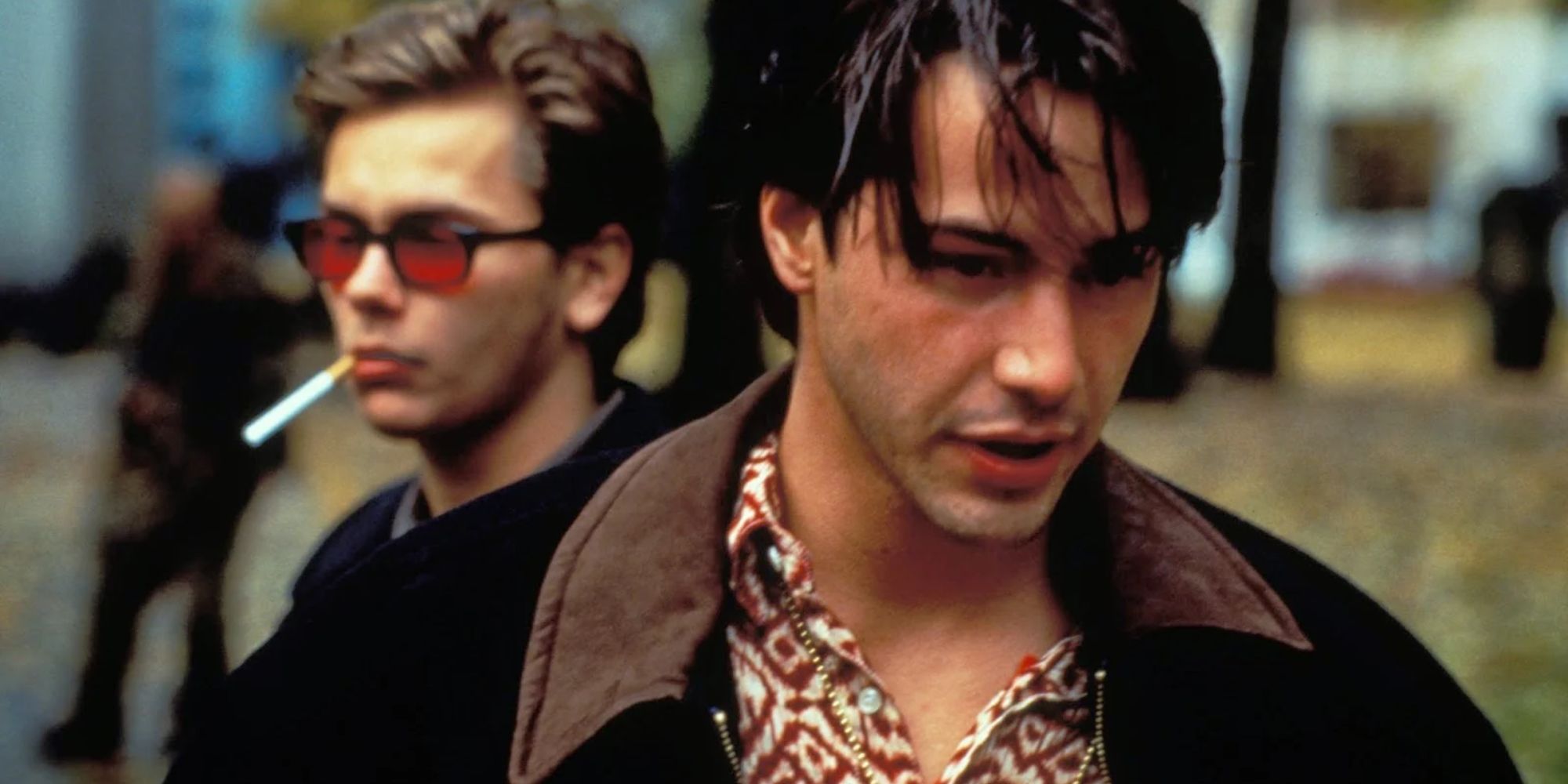 Keanu Reeves and River Phoenix standing behind him in My Own Private Idaho