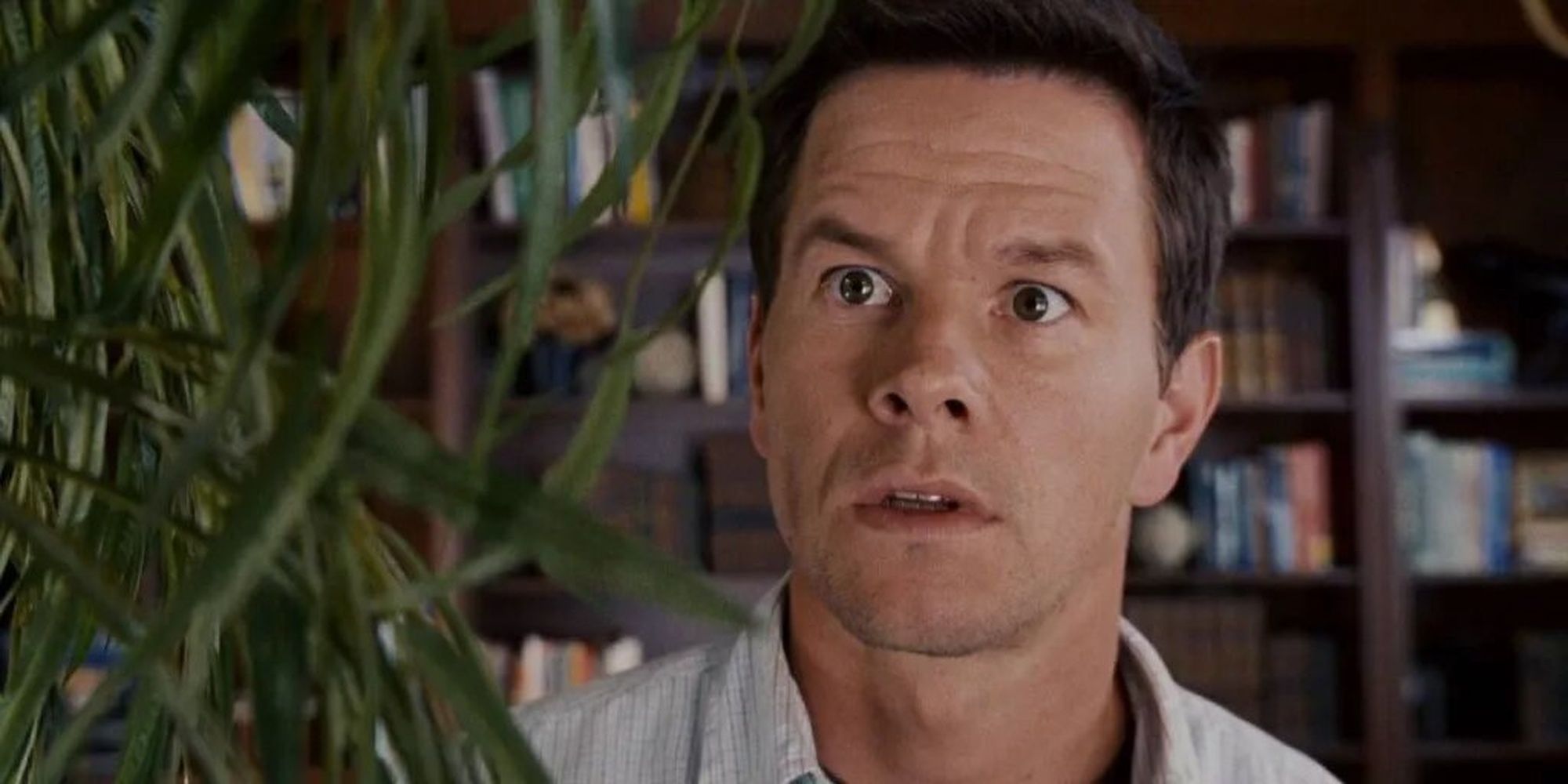 Elliot, played by Mark Wahlberg, looks concerned while talking to a house plant