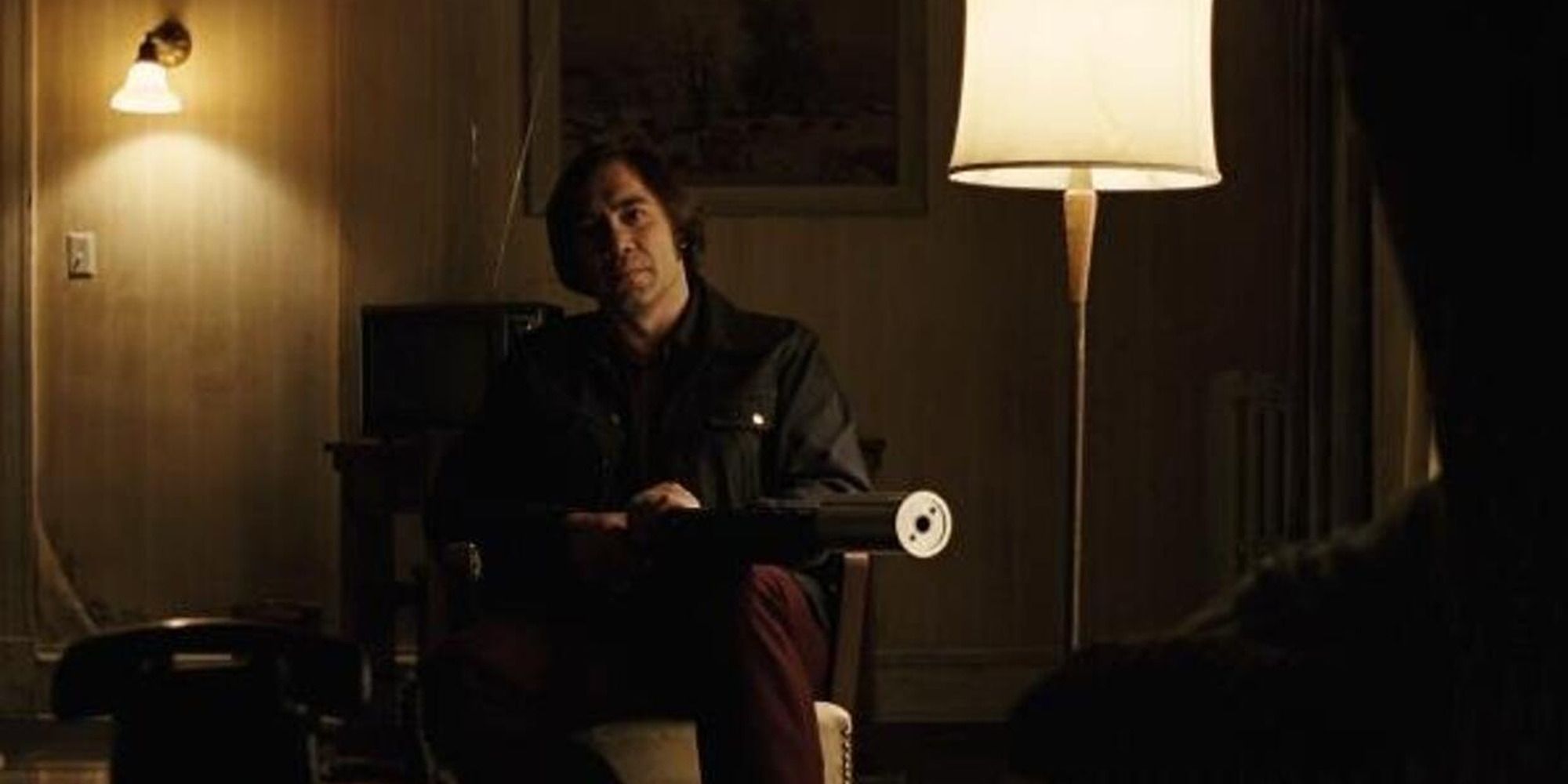 Anton Chigurh from No Country for Old Men, pointing his gun at an unseen figure