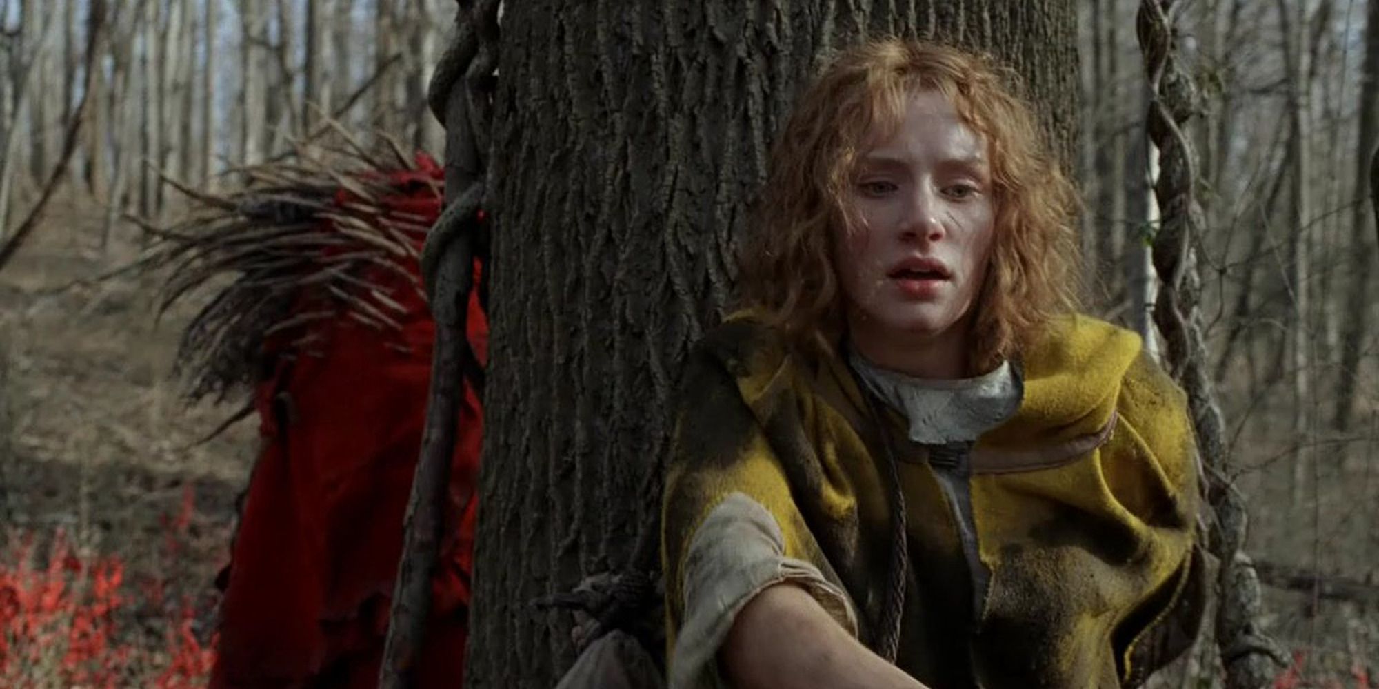 Bryce Dallas Howard se cache derrière un arbre alors qu'une silhouette rouge la traque dans le film Le Village.