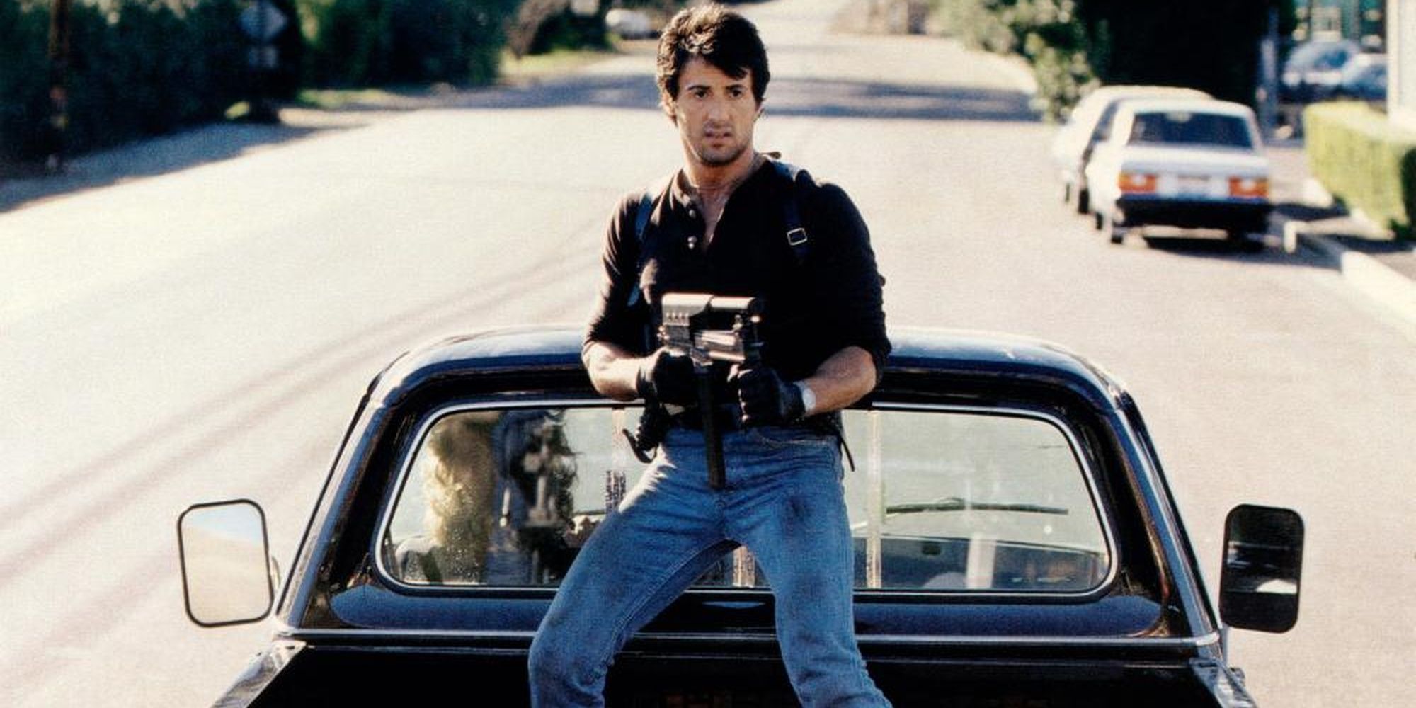Sylvester Stallone wielding a machine gun in the back of a truck in Cobra