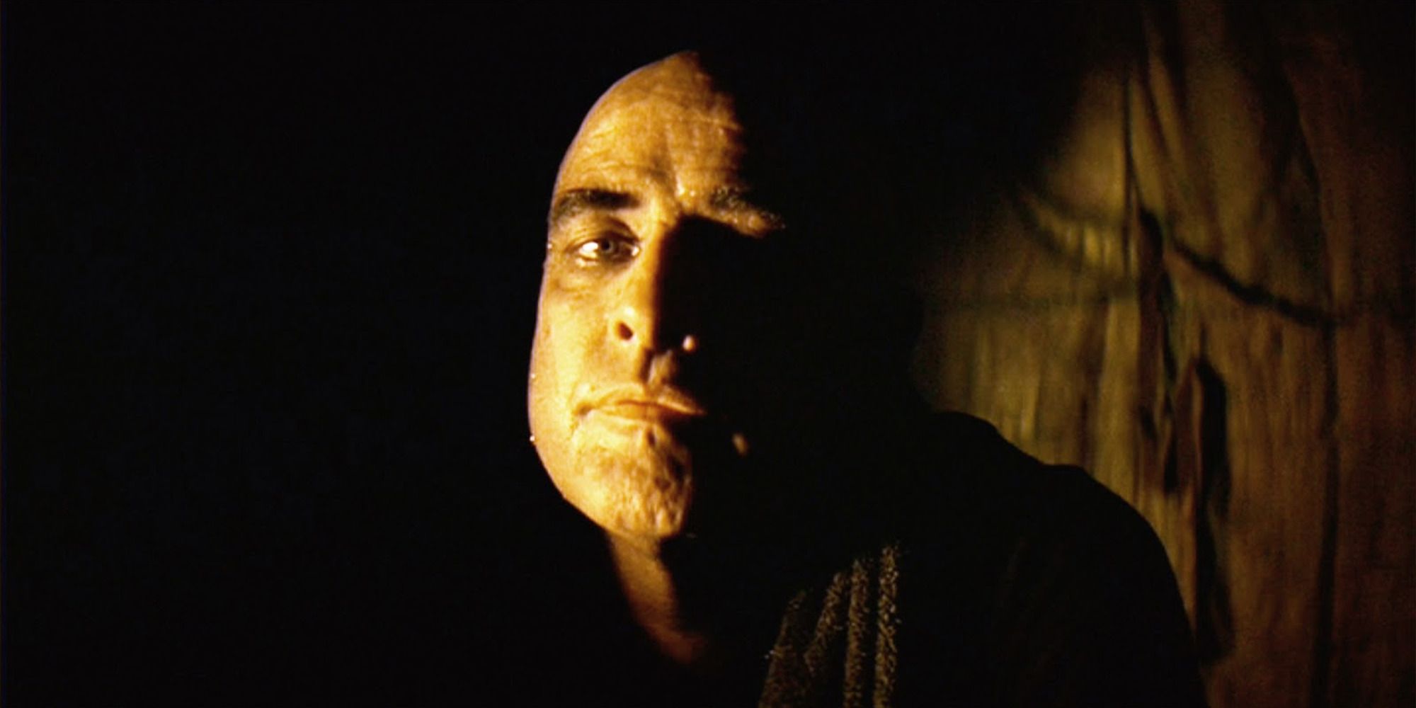 Le colonel Kurtz d'Apocalypse Now, se profilant dans l'ombre, fixant la caméra.