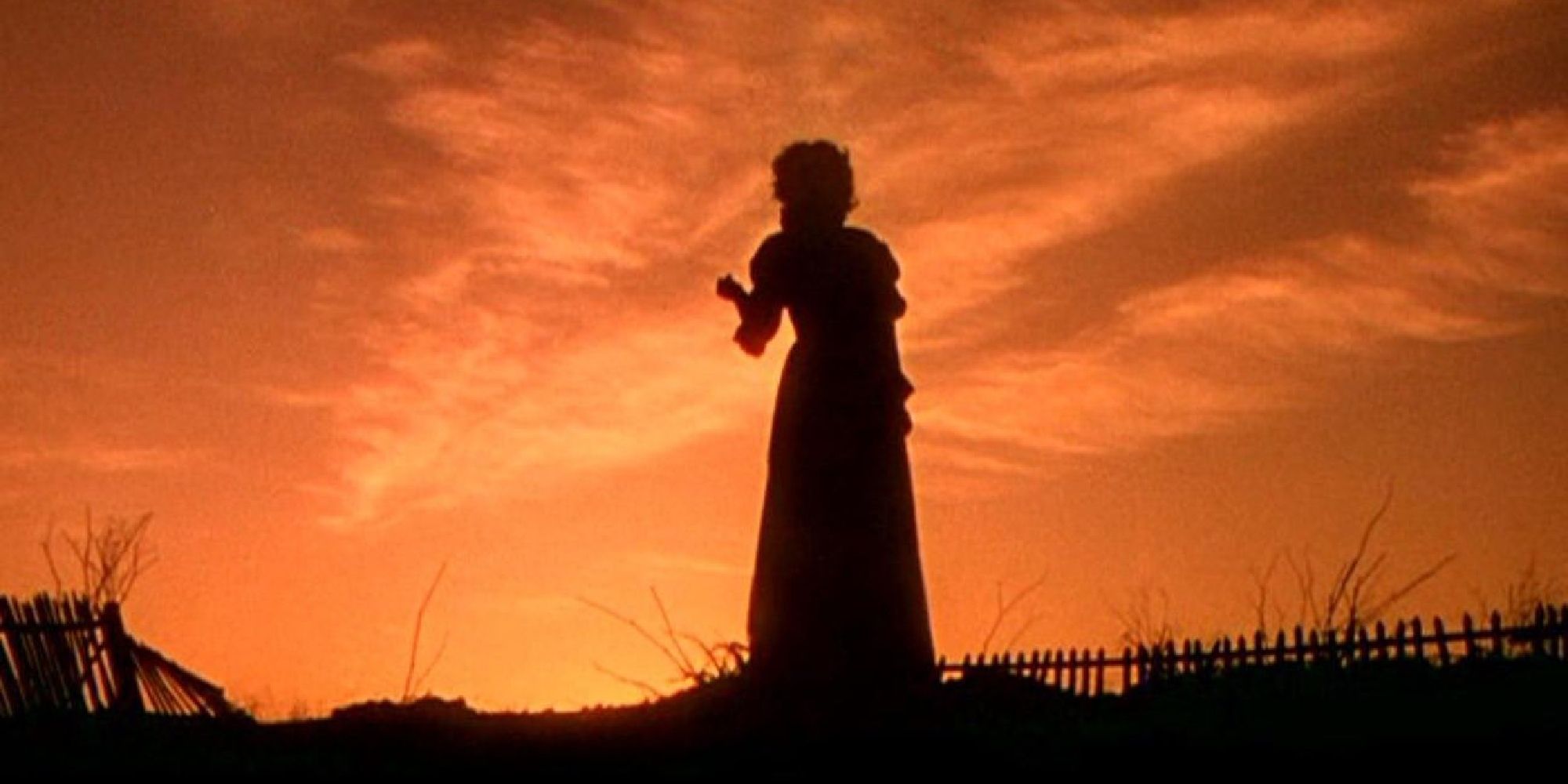 Scarlett O&rsquo;Hara stands in a field. The sun is setting behind her in Gone with the Wind.