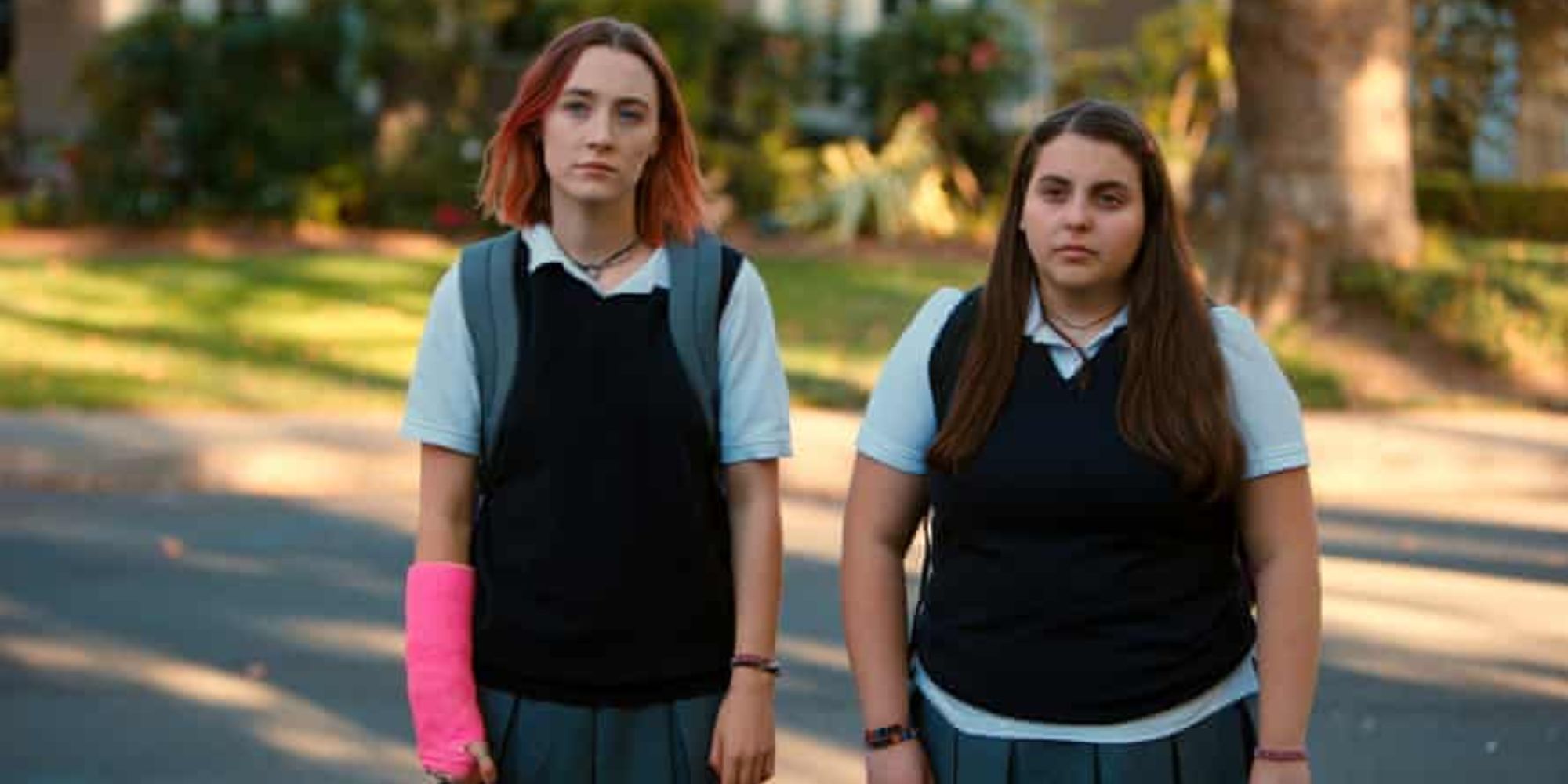 Saoirse Ronan as Lady Bird wearing a cast standing next to Beanie Feldstein as Julie in Lady Bird