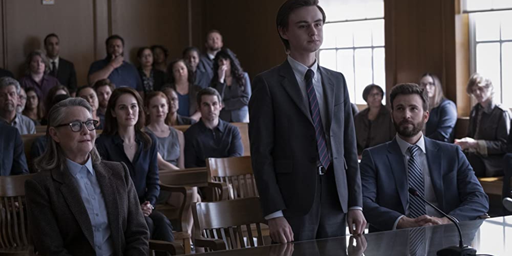 Jacob Barder (Jaeden Martell) stands in a courtroom with his father, Andy Barber (Chris Evans), and Joanna Klein (Cherry Jones)