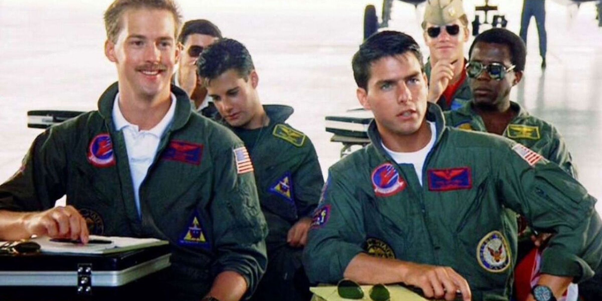 Maverick (Tom Cruise) and Goose (Anthony Edwards) from Top Gun sitting at their desks