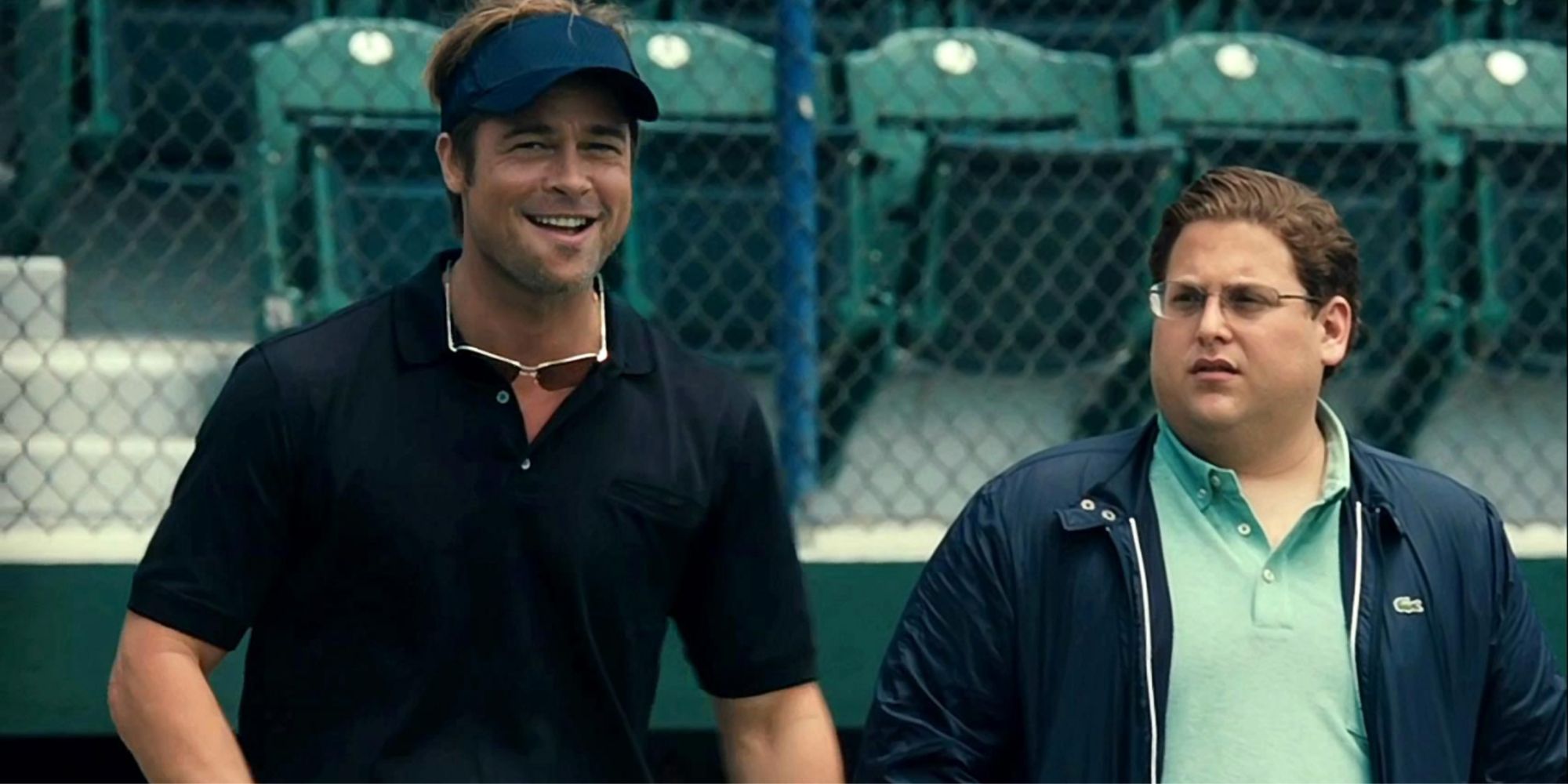 Brad Pitt as Billy Beane and Jonah Hill as Peter Brand stand near a baseball diamond in the film Moneyball