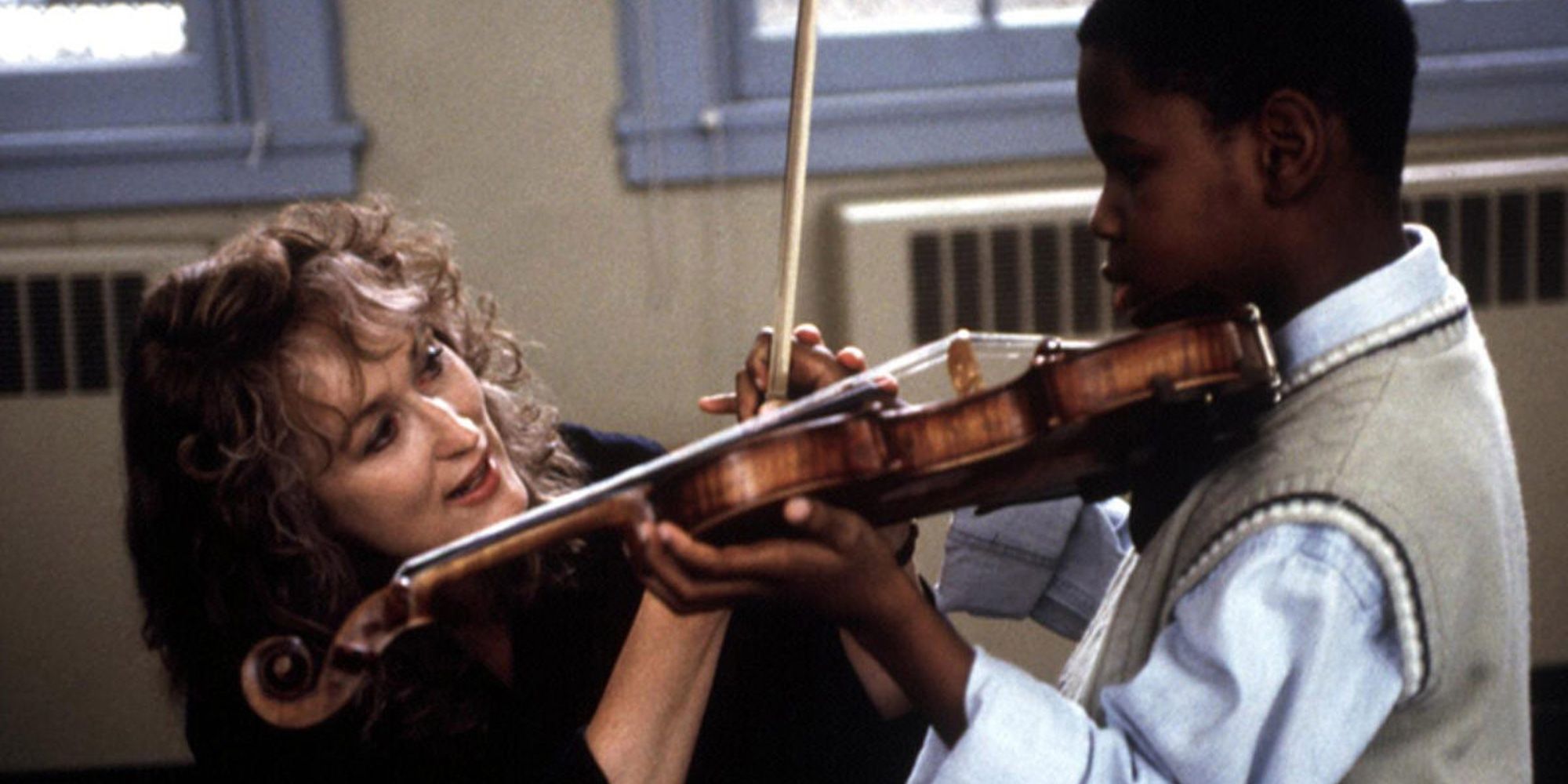 Meryl Streep helps a student play the violin in Music of the Heart