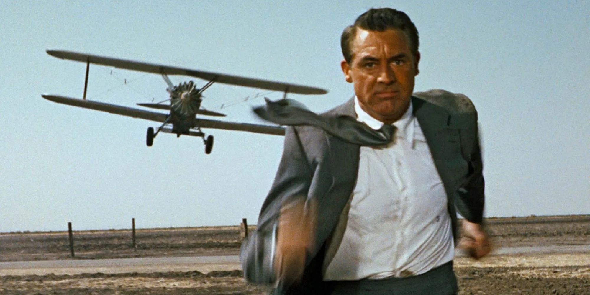 Cary Grant as Roger Thornhill, wearing a suit and running away from a crop duster plane in North by Northwest