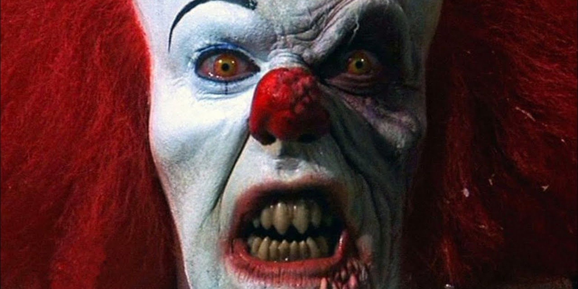 Pennywise in IT 1990 looking menacing and staring with teeth out