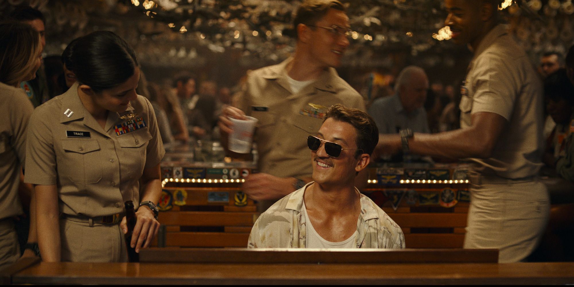 Rooster from Top Gun: Maverick playing the piano in a bar with a female Marine looking at him
