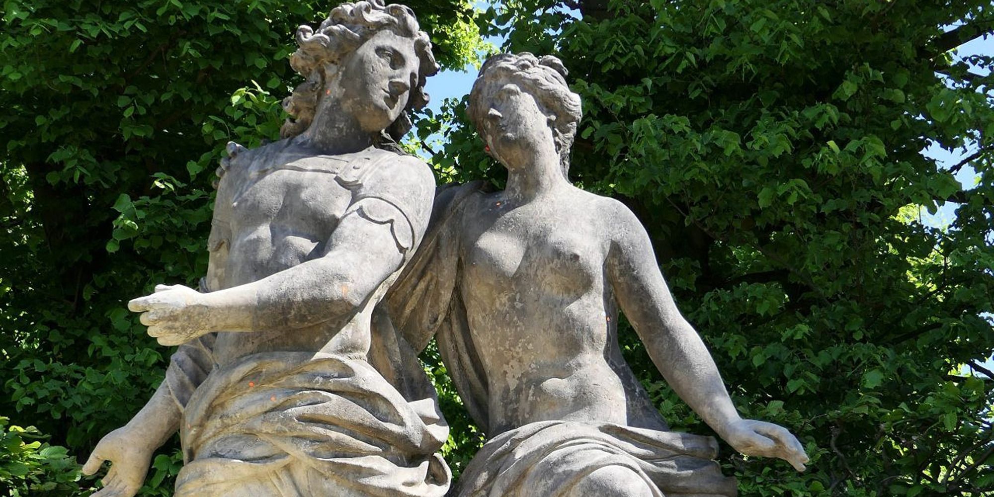 a sculpture of a man and woman in robes, looking at each other with love