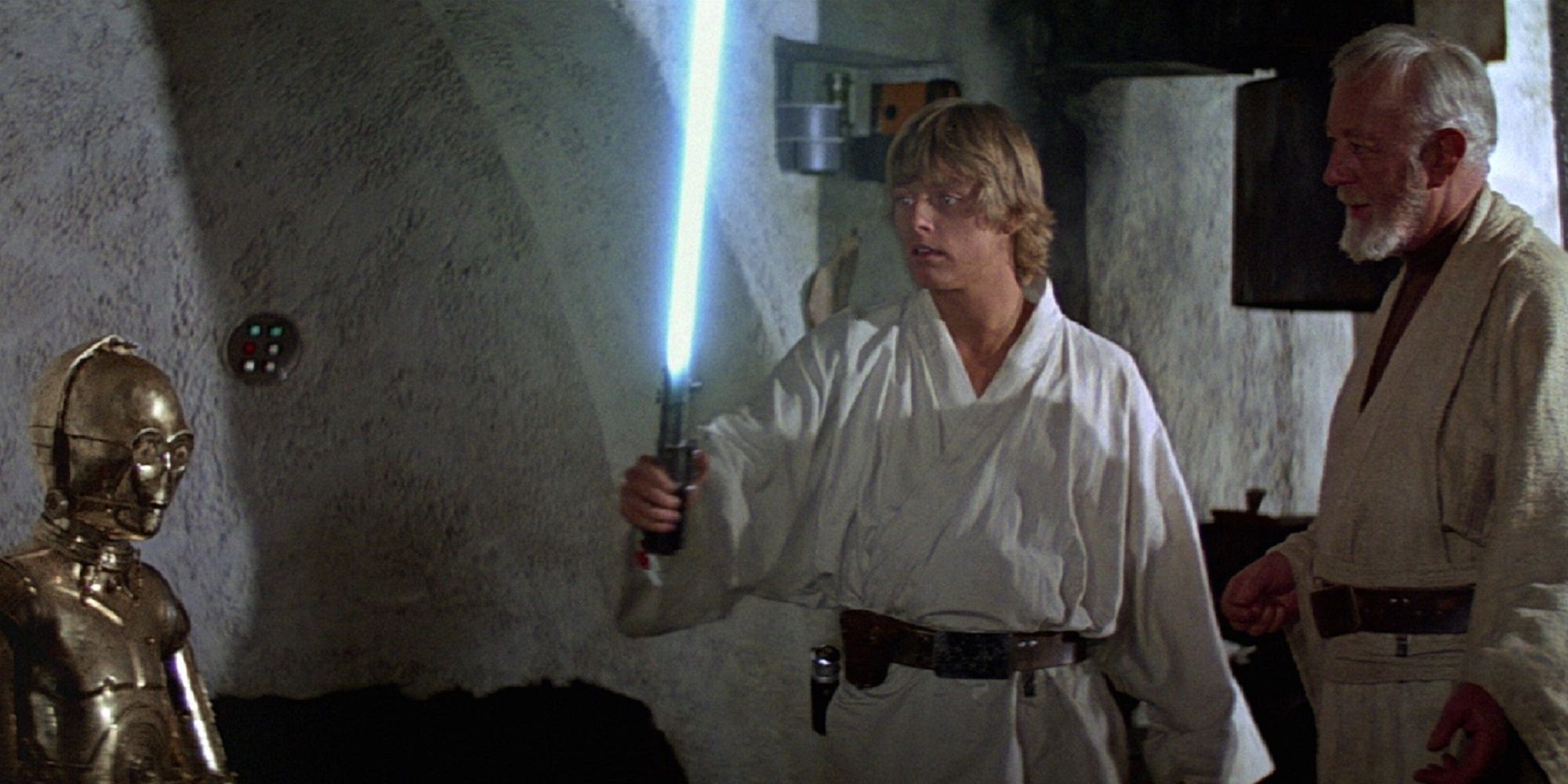 Luke Skywalker with his blue lightsaber and Obi Wan Kenobi and C-3PO in Star Wars.