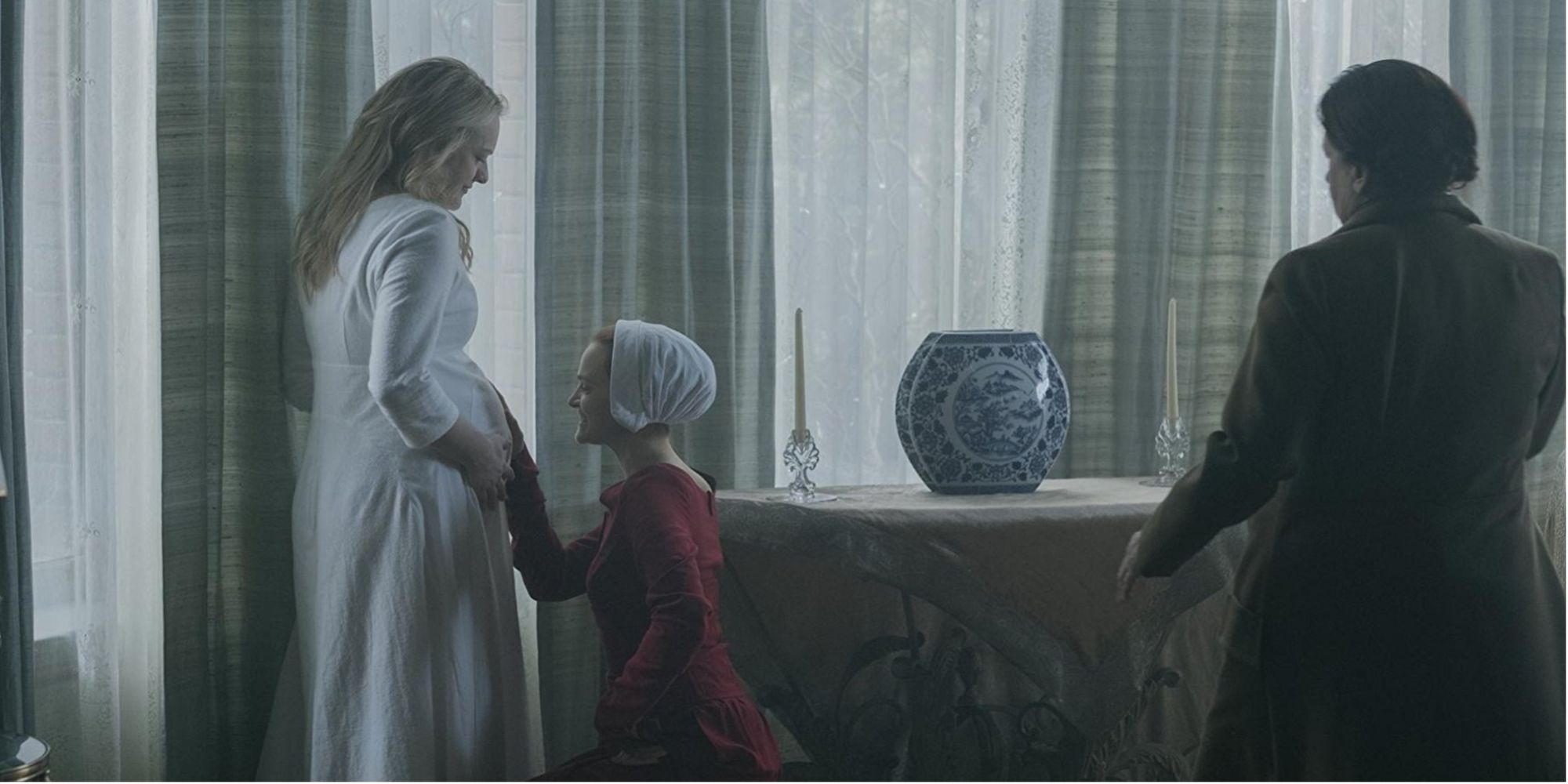 Janine rubs June&rsquo;s pregnant stomach, while Lydia watches