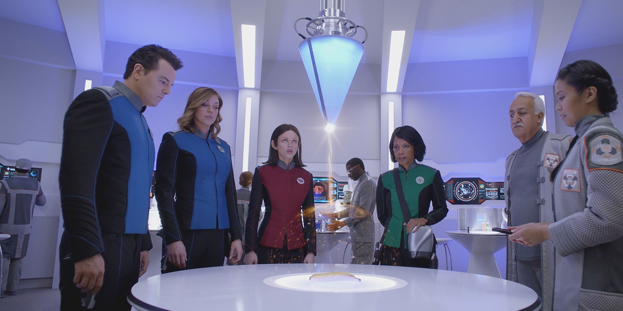 The cast of The Orville standing around a table looking at a hologram map.