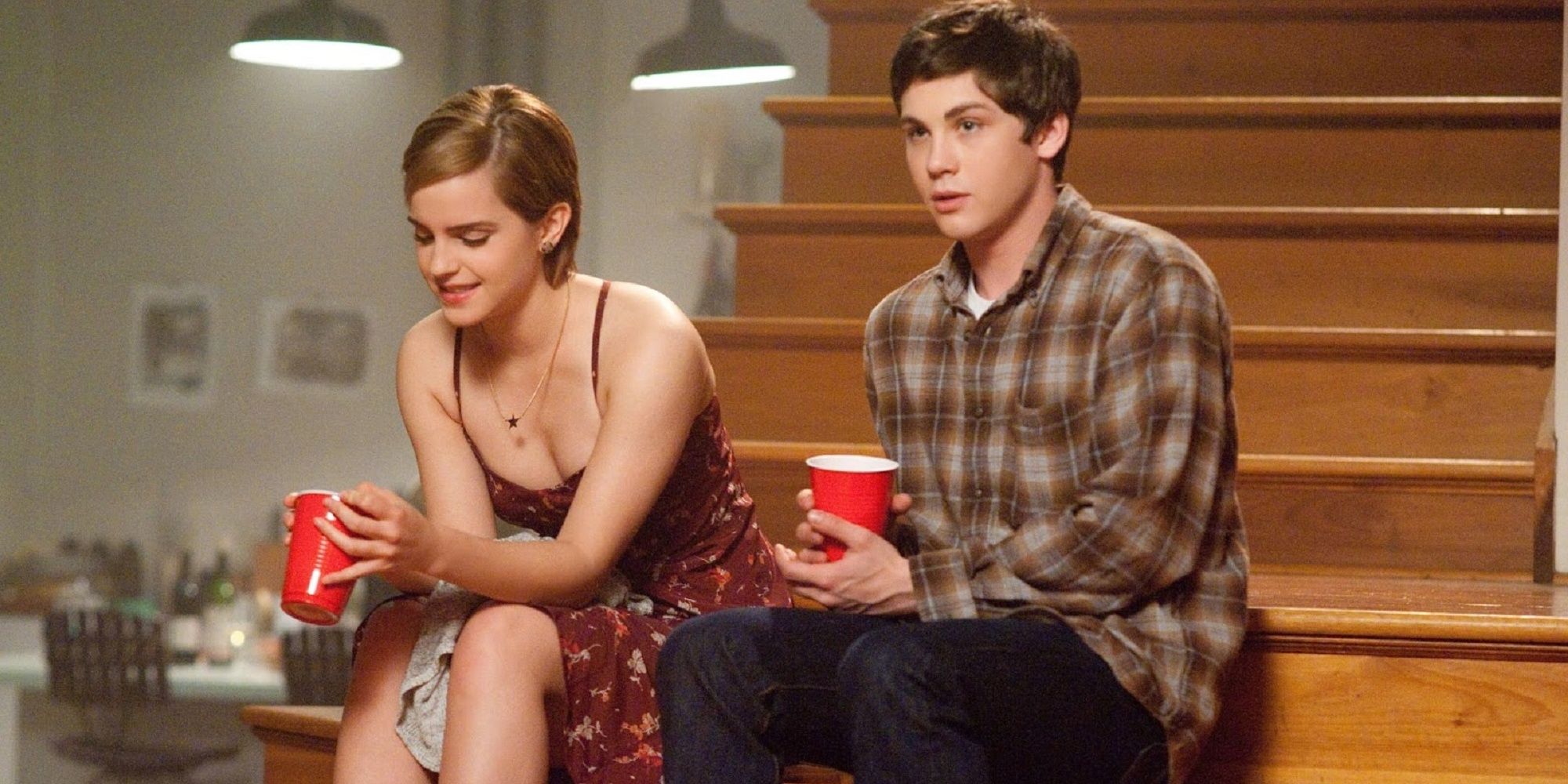 Sam and Charlie sitting on some stairs holding red cups in The Perks of Being a Wallflower.