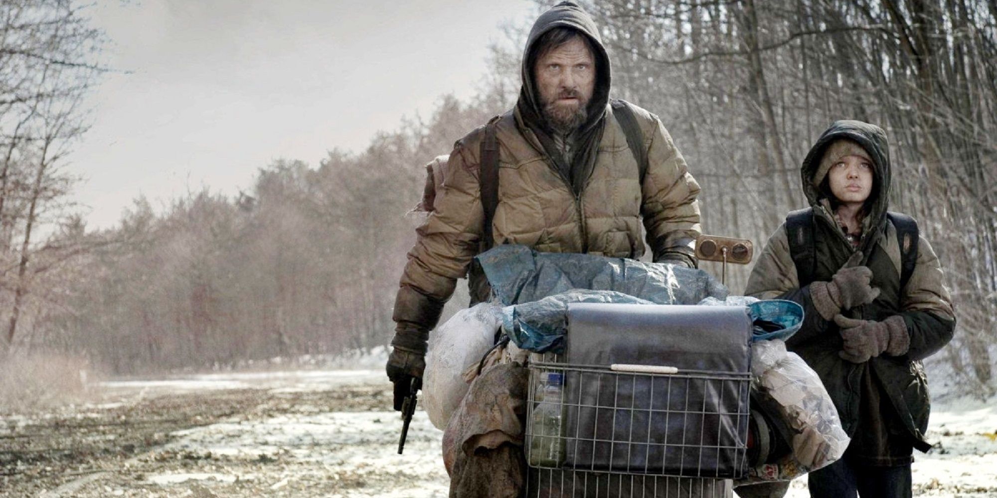 A man and his young son pushing a shopping cart on The Road.