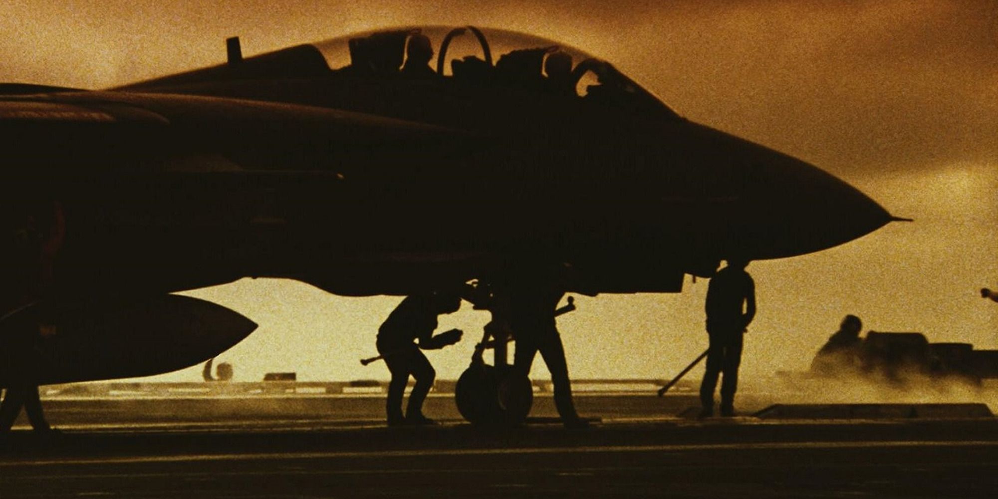 a team preparing a military plane for takeoff in front of the sunset from Top Gun