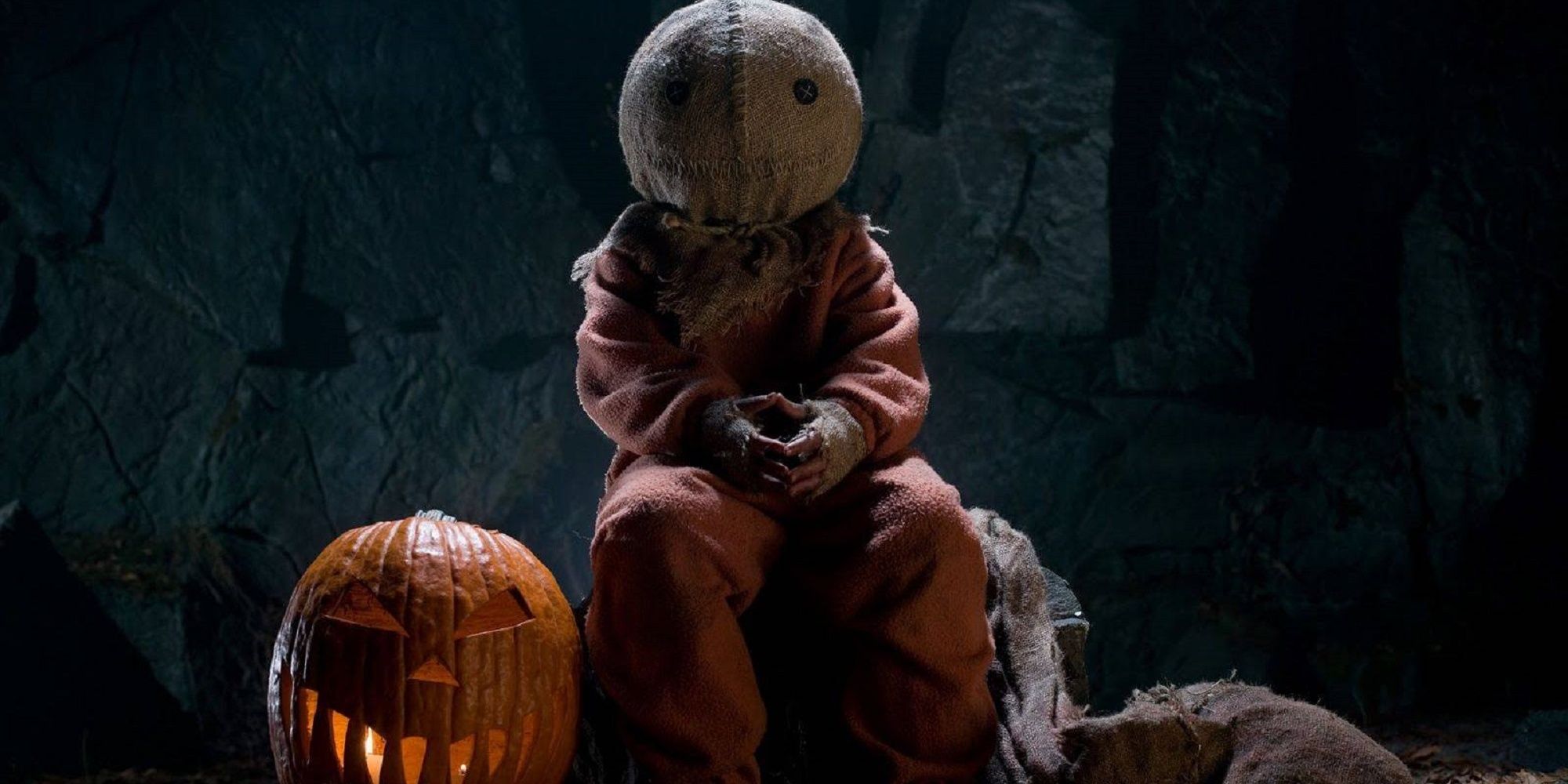 Sam sitting on a log next to a pumpkin in Trick 'r Treat.