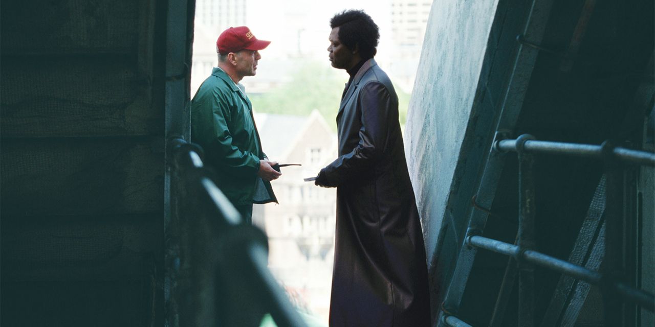 Two men converse in a shady stairwell.