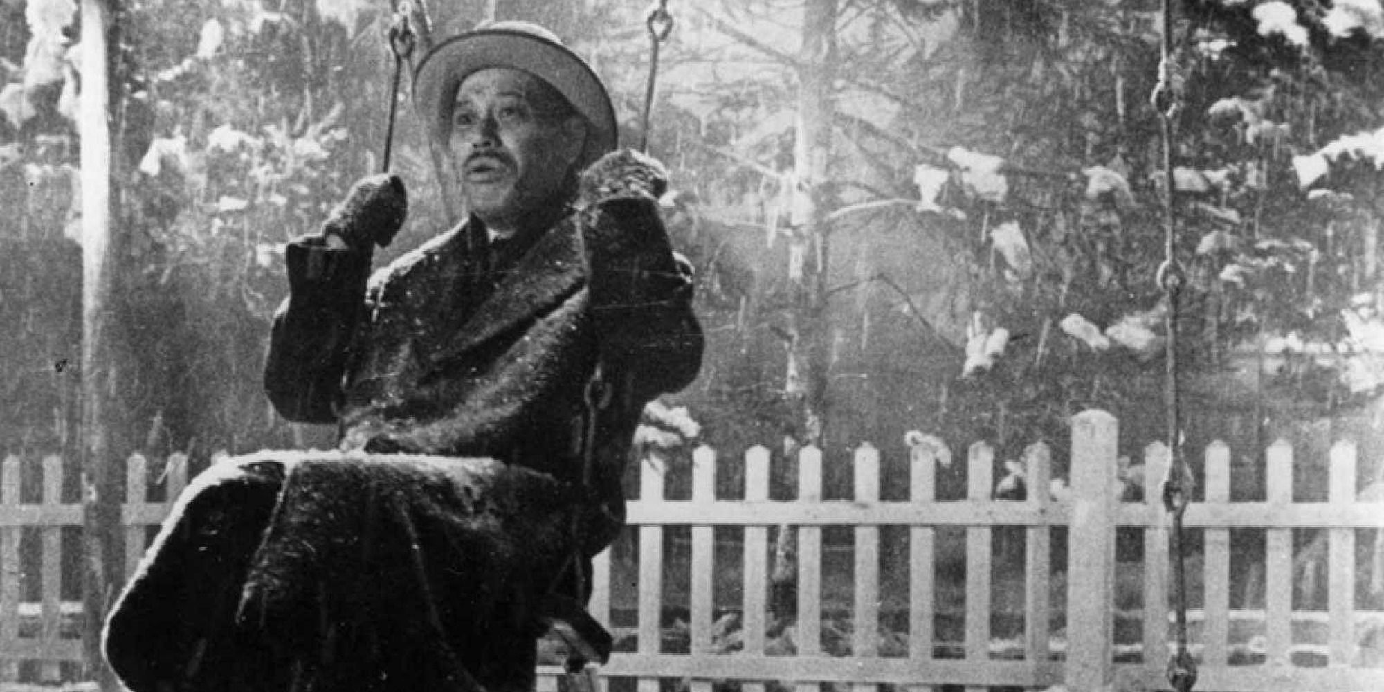 An elderly man in a park's swings under the snow