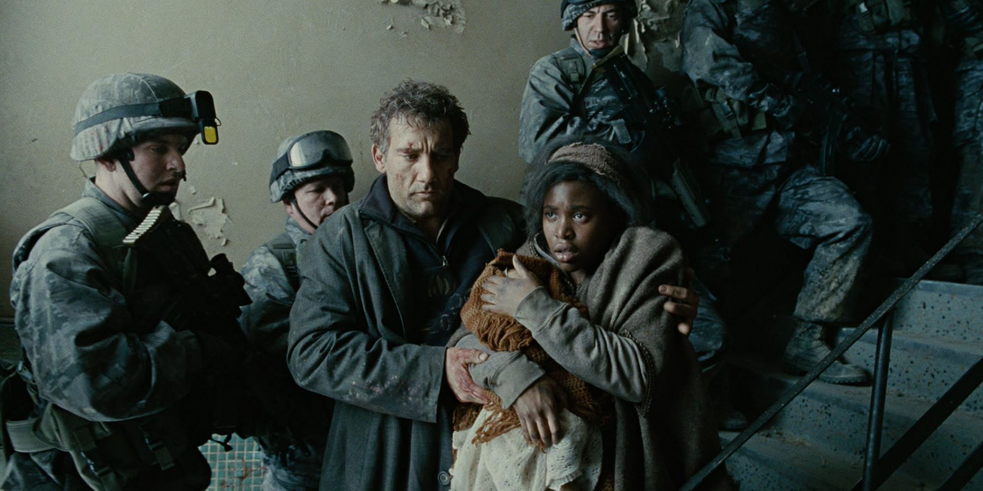 Theo (Clive Owen) and Kee (Clare-Hope Ashitey) walking past soldiers with a baby in 'Children of Men' (2006)