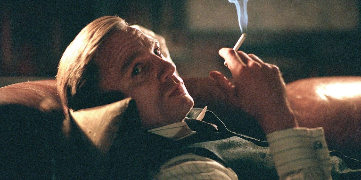 Conor Rooney laying down and smoking while looking off-camera in Road to Perdition