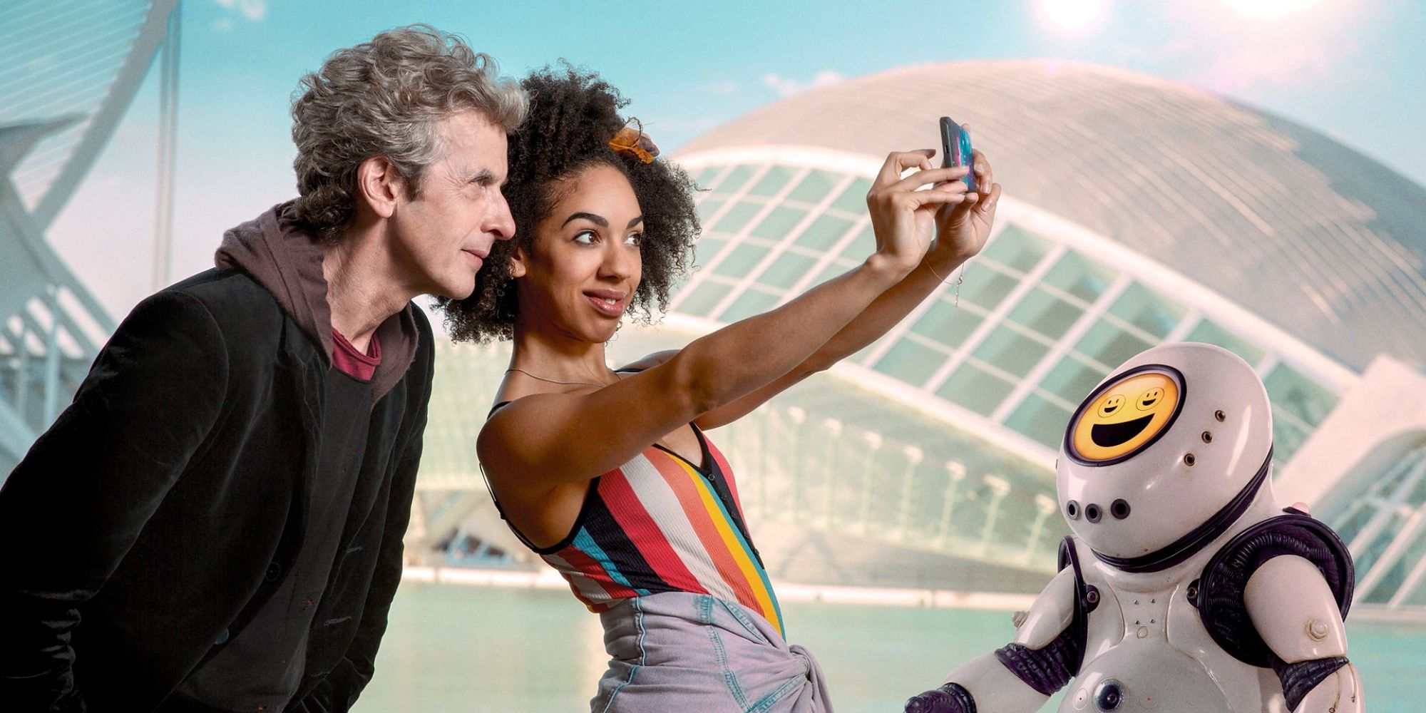 The Doctor and Bill Potts taking a selfie with an EmojiBot