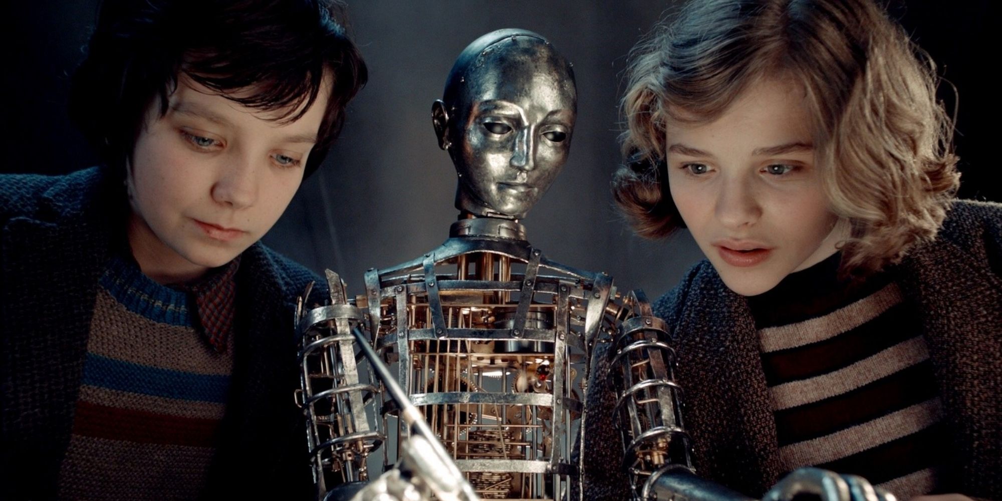 Hugo (Asa Butterfield) and Isabelle (Chloë Grace Moretz) beside an automaton in 'Hugo' (2011)