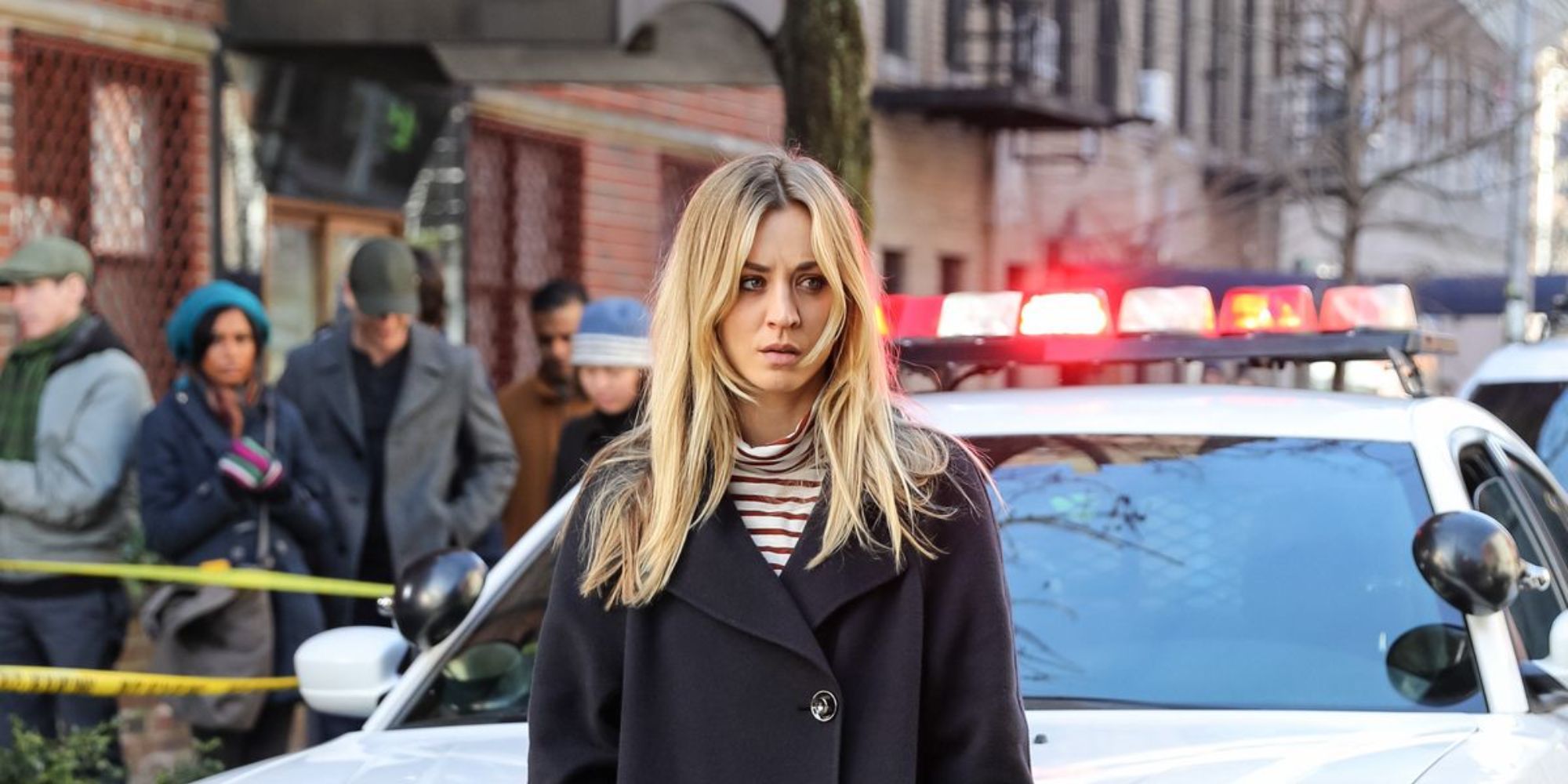 A blonde woman standing in front of a cop car