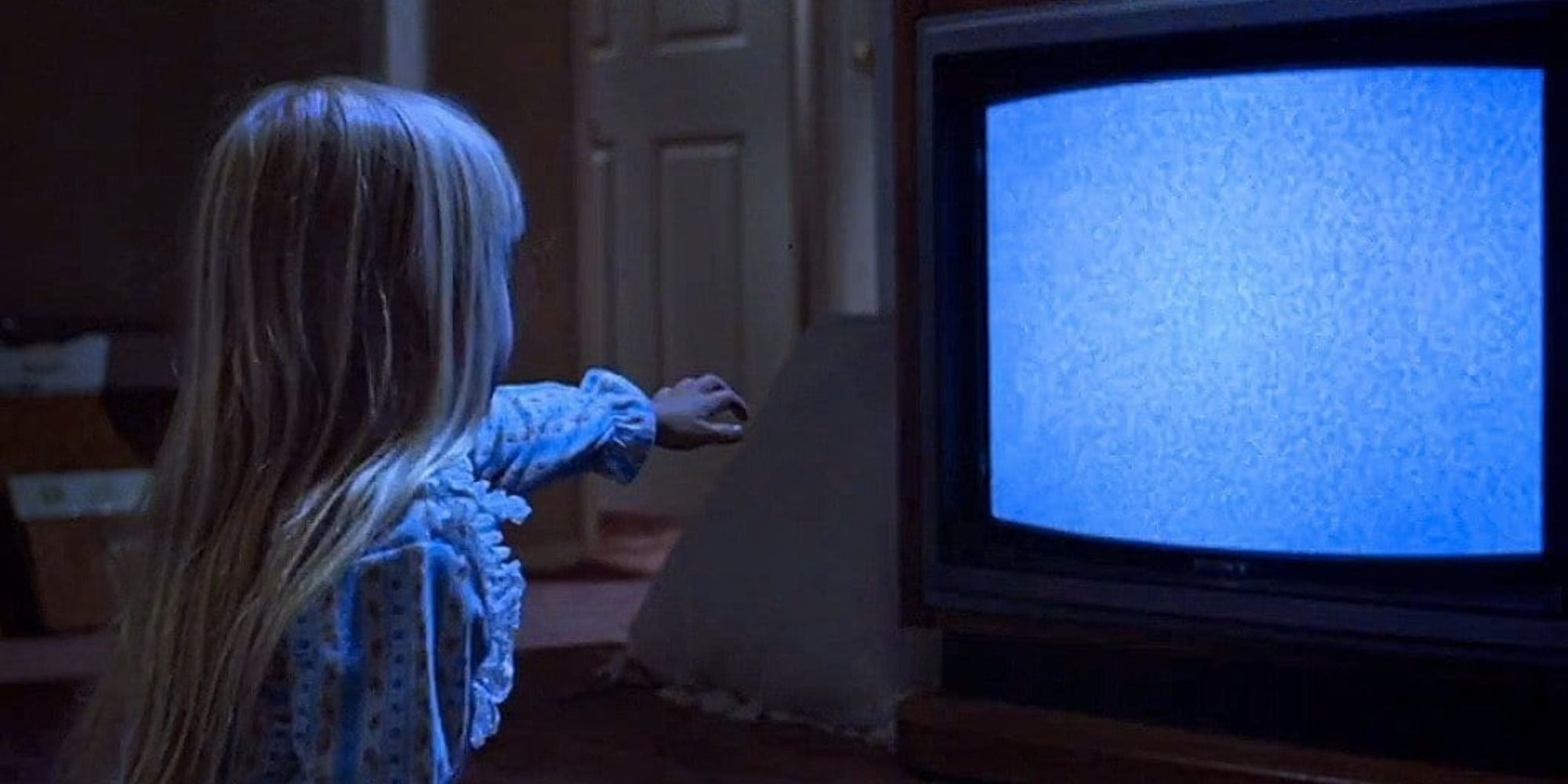 A little girl pointing at a TV filled with static